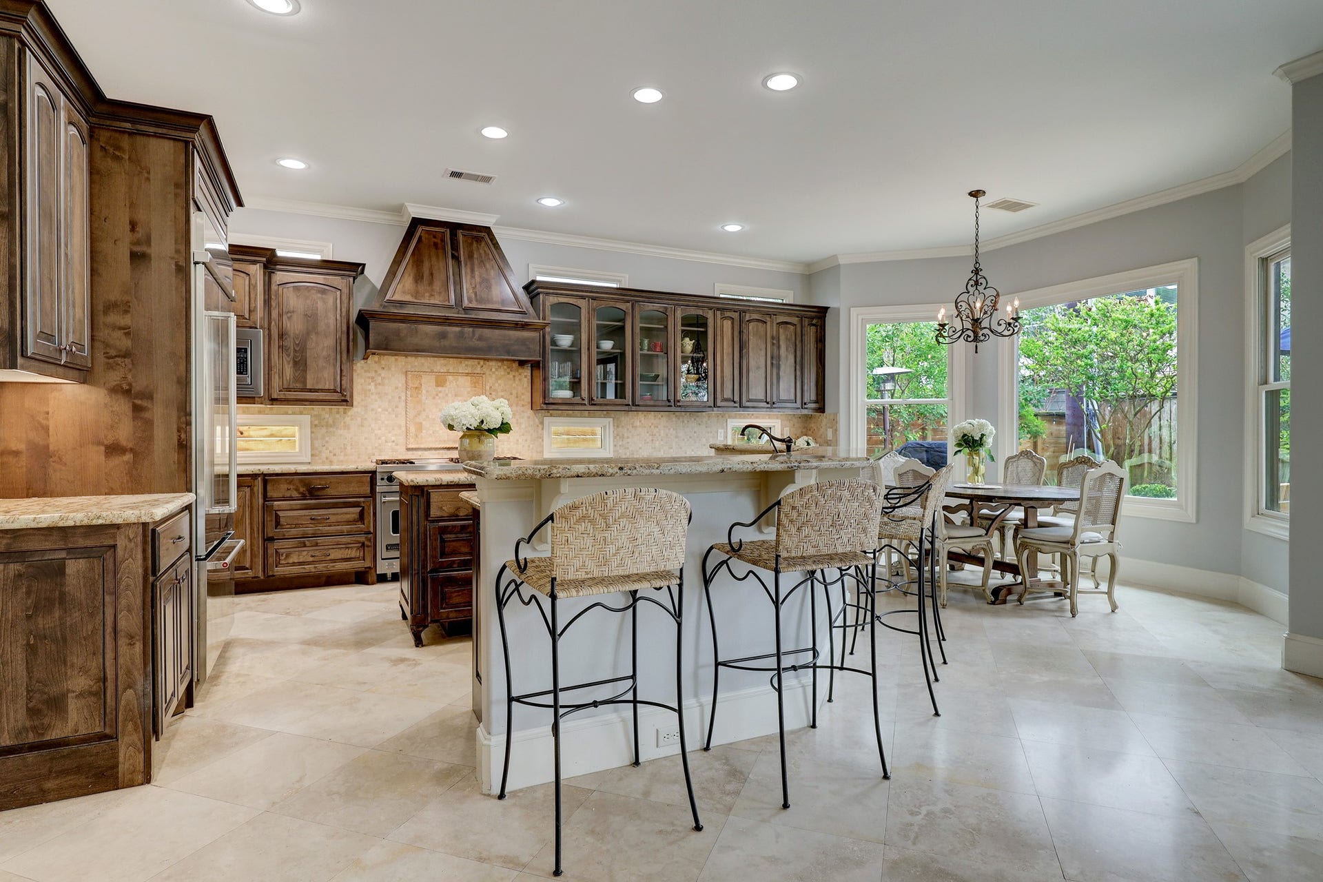 6004 Lake Street, Houston, TX 77005 Spacious kitchen with beautiful wood cabinetry, a large island bar with seating, and a breakfast room bathed in natural light from expansive windows.