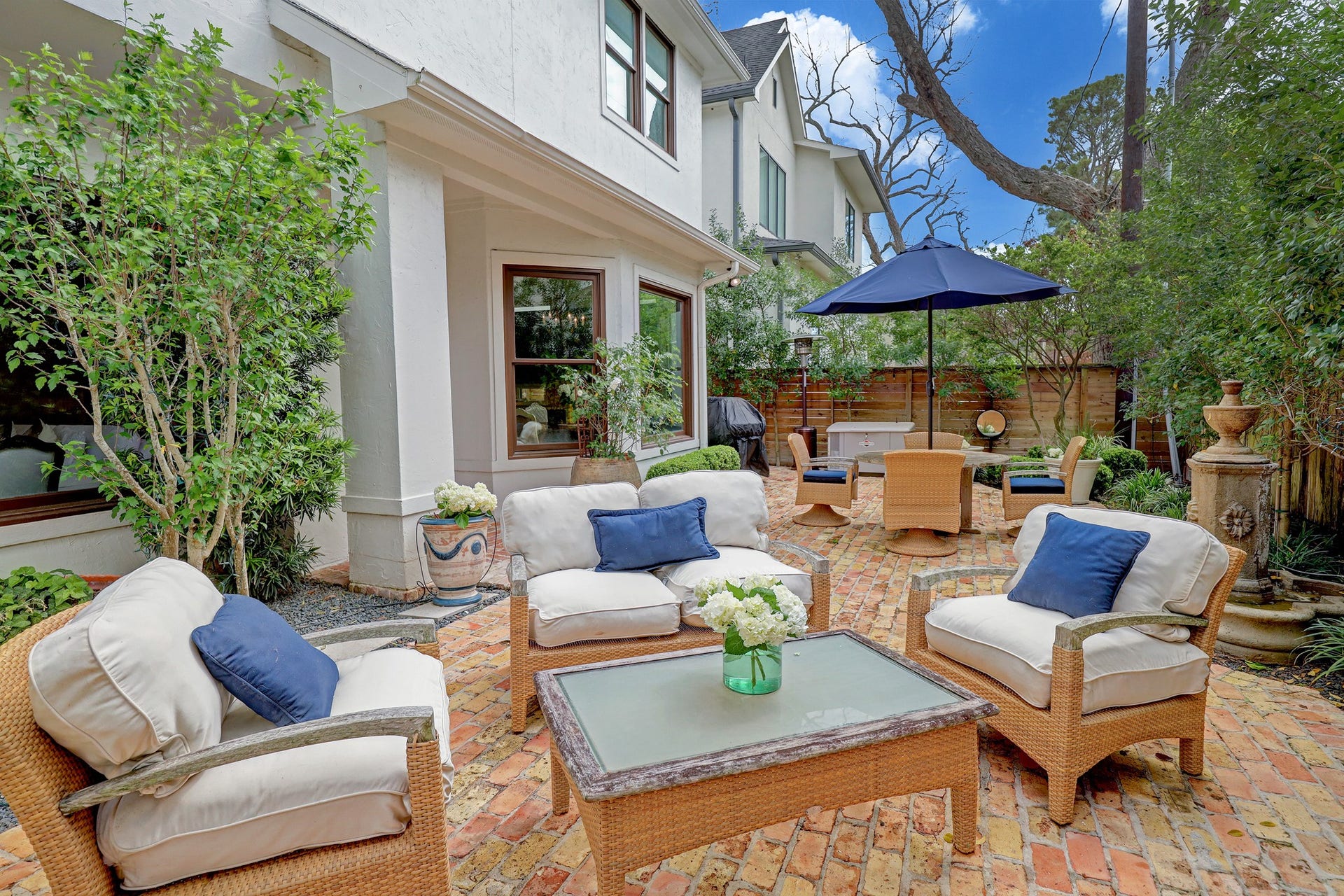 6004 Lake Street, Houston, TX 77005 Charming outdoor patio with comfortable seating, lush greenery, and a stylish umbrella, perfect for relaxing or entertaining.
