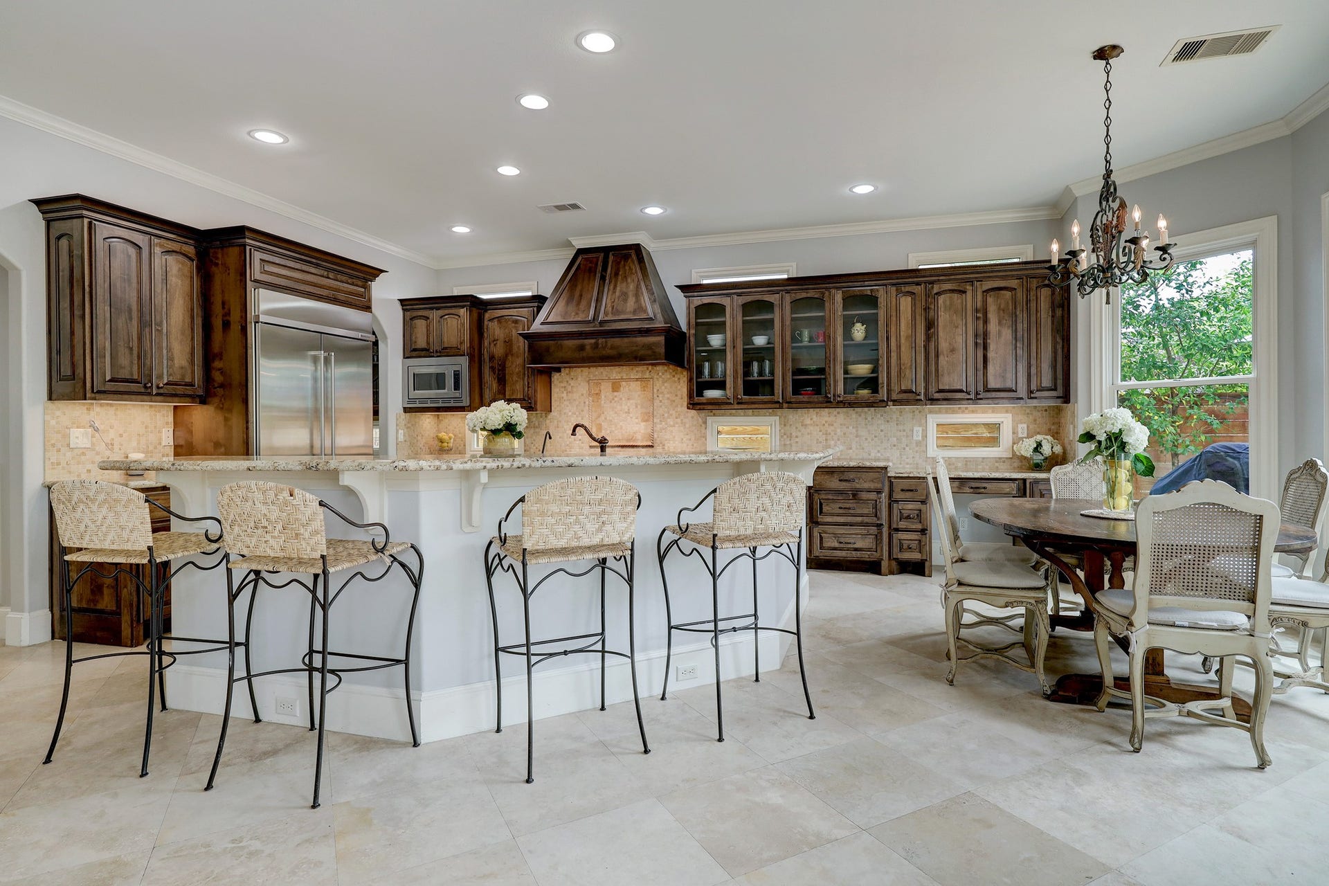 6004 Lake Street, Houston, TX 77005 Spacious kitchen with dark wood cabinetry, a large central island with bar seating, and a breakfast room with a chandelier (reserved), perfect for entertaining.