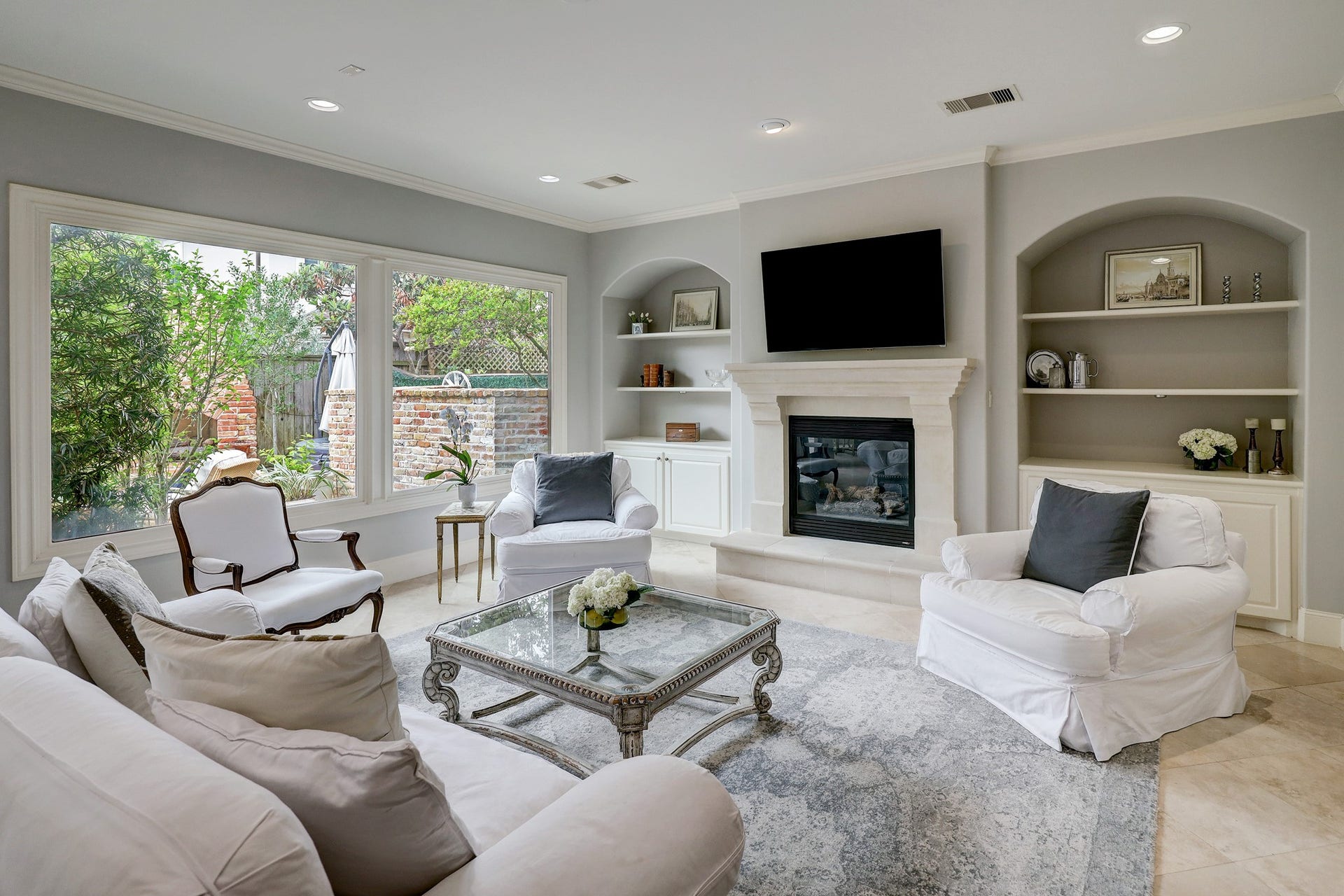 6004 Lake Street, Houston, TX 77005 Spacious family room featuring a limestone fireplace with built-in shelving and large windows offering abundant natural light.