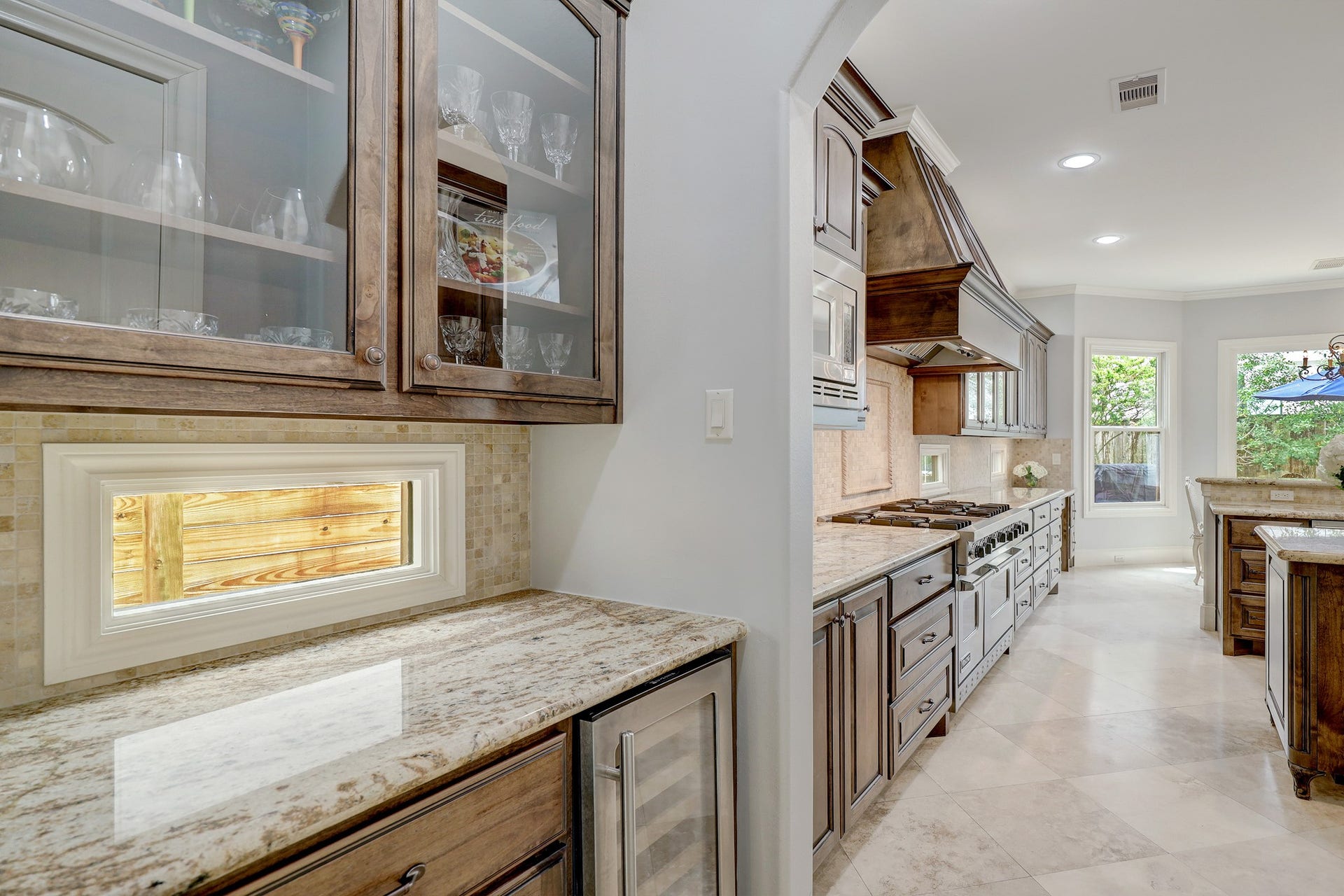 6004 Lake Street, Houston, TX 77005 This kitchen features rich wooden cabinetry, sleek countertops, and high-end stainless steel appliances, with ample natural light streaming through large windows.