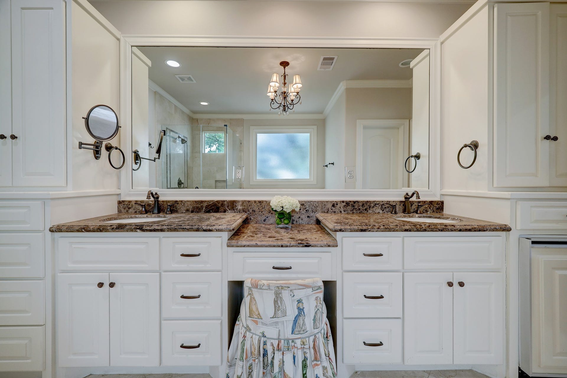 6004 Lake Street, Houston, TX 77005 The primary bathroom features a spacious double vanity with expansive countertops, ample cabinetry, and a large mirror, complemented by a charming chandelier and natural light.