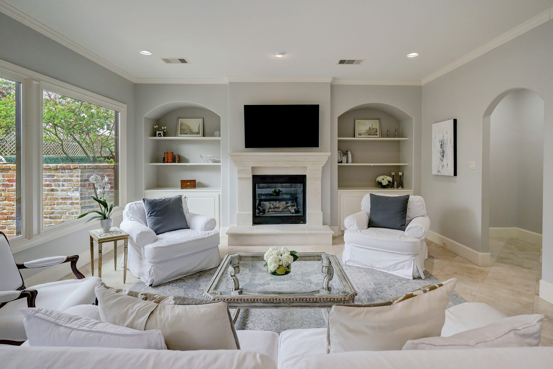 6004 Lake Street, Houston, TX 77005 Spacious family room featuring a limestone fireplace with built-in shelving and large windows offering abundant natural light.