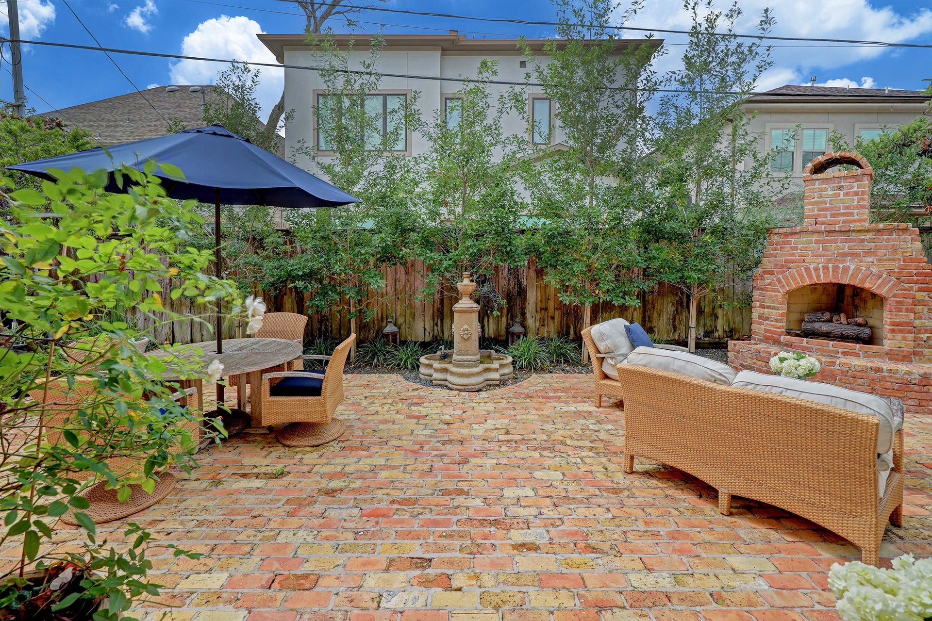 6004 Lake Street, Houston, TX 77005 Charming brick patio featuring a cozy outdoor fireplace, elegant fountain, and comfortable seating, perfect for relaxing or entertaining. GENERATOR CONVEYS!