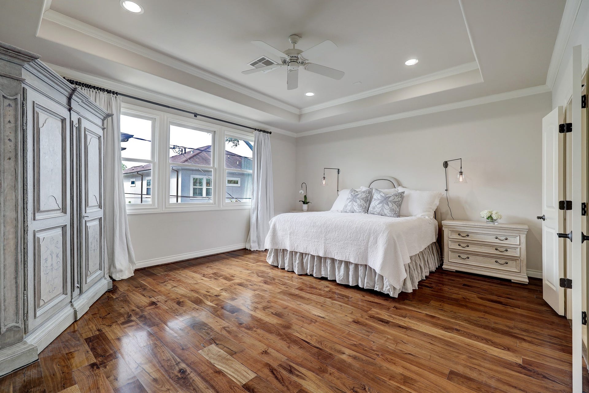 6004 Lake Street, Houston, TX 77005 Spacious primary bedroom with elegant wood flooring, and ample natural light streaming through large windows, creating a serene and inviting atmosphere.
