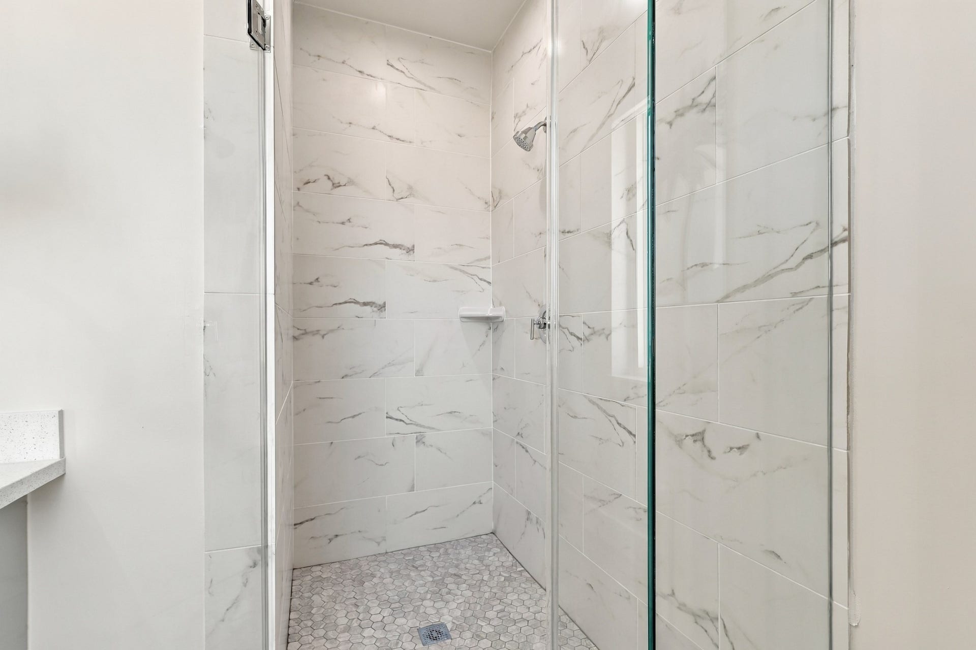 17211 Termini San Luis Pass Rd, Galveston, TX 77554 Walk-in shower detail
A glass enclosure showcases the showers elegant marble-look wall tile and mosaic floor. A built-in corner shelf adds convenient storage while maintaining the streamlined design.