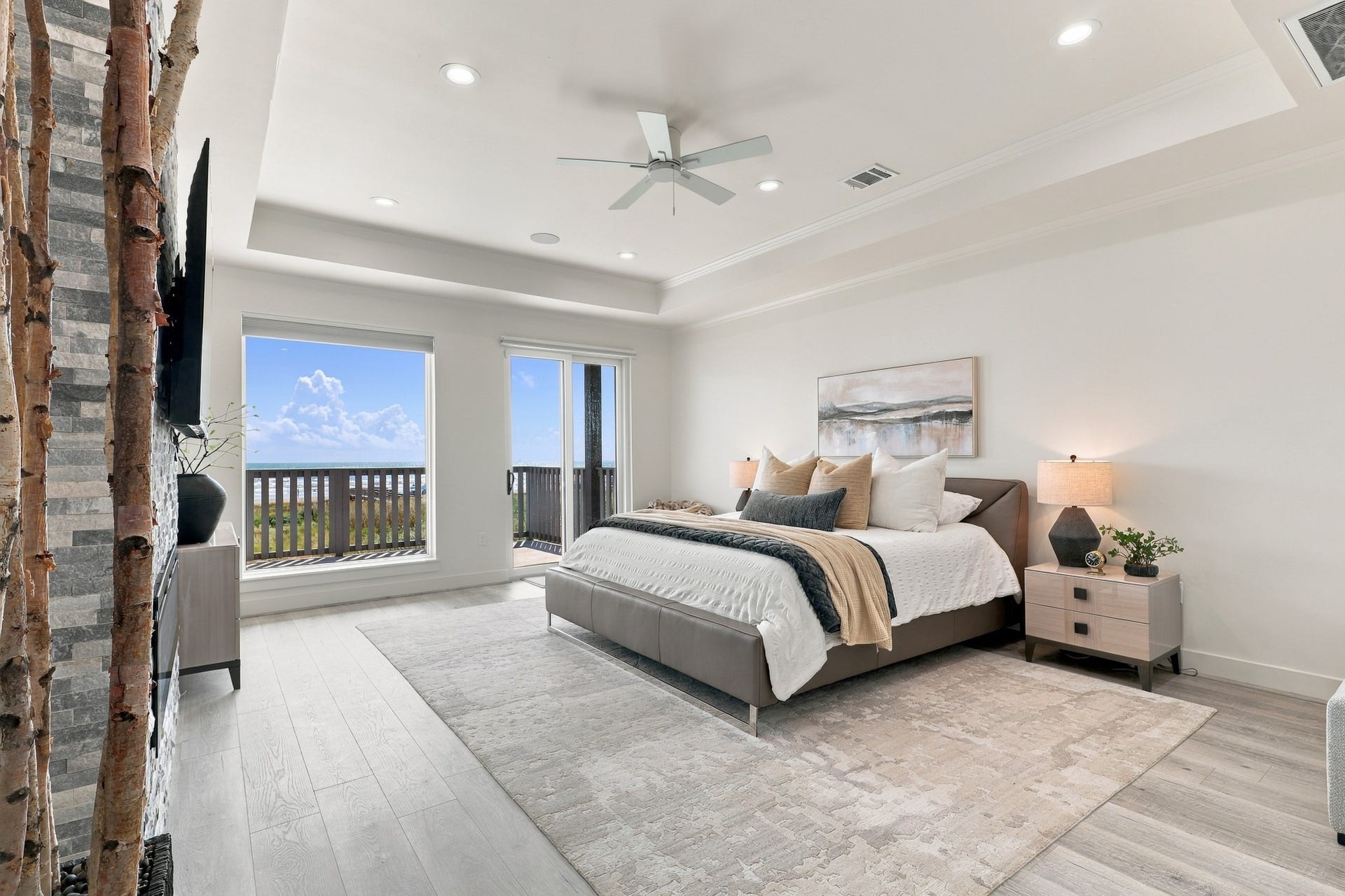 17211 Termini San Luis Pass Rd, Galveston, TX 77554 Primary Bedroom- Wake to Gulf views in this spacious bedroom featuring a tray ceiling, recessed lighting, and a textured fireplace accent wall. Sliding glass doors provide direct access to the beachfront deck.