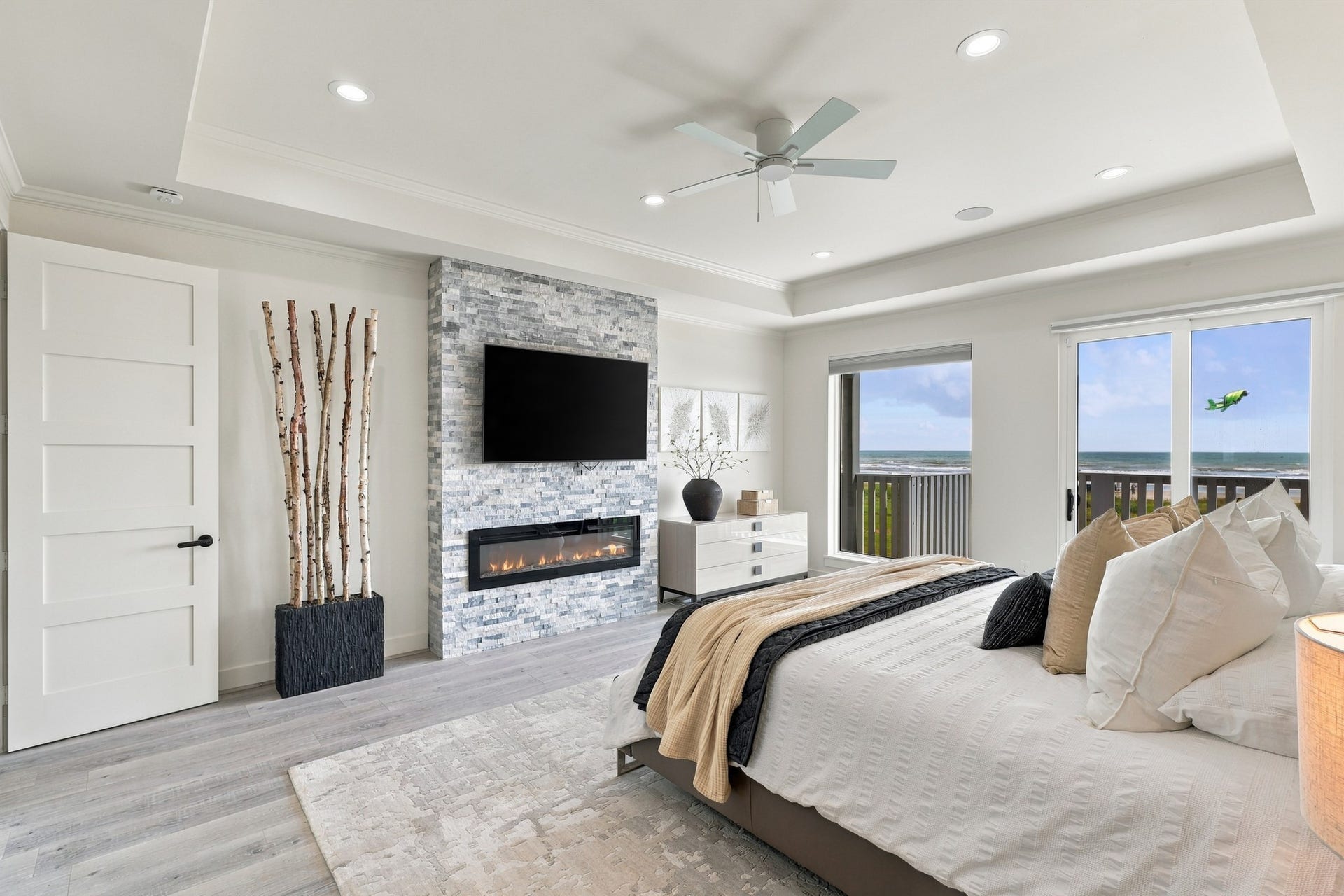 17211 Termini San Luis Pass Rd, Galveston, TX 77554 Primary bedroom and fireplace
The primary retreat features a stacked-stone fireplace wall, an architectural tray ceiling, and direct access to the beachfront deck. Generous windows bring Gulf views into this inviting space.