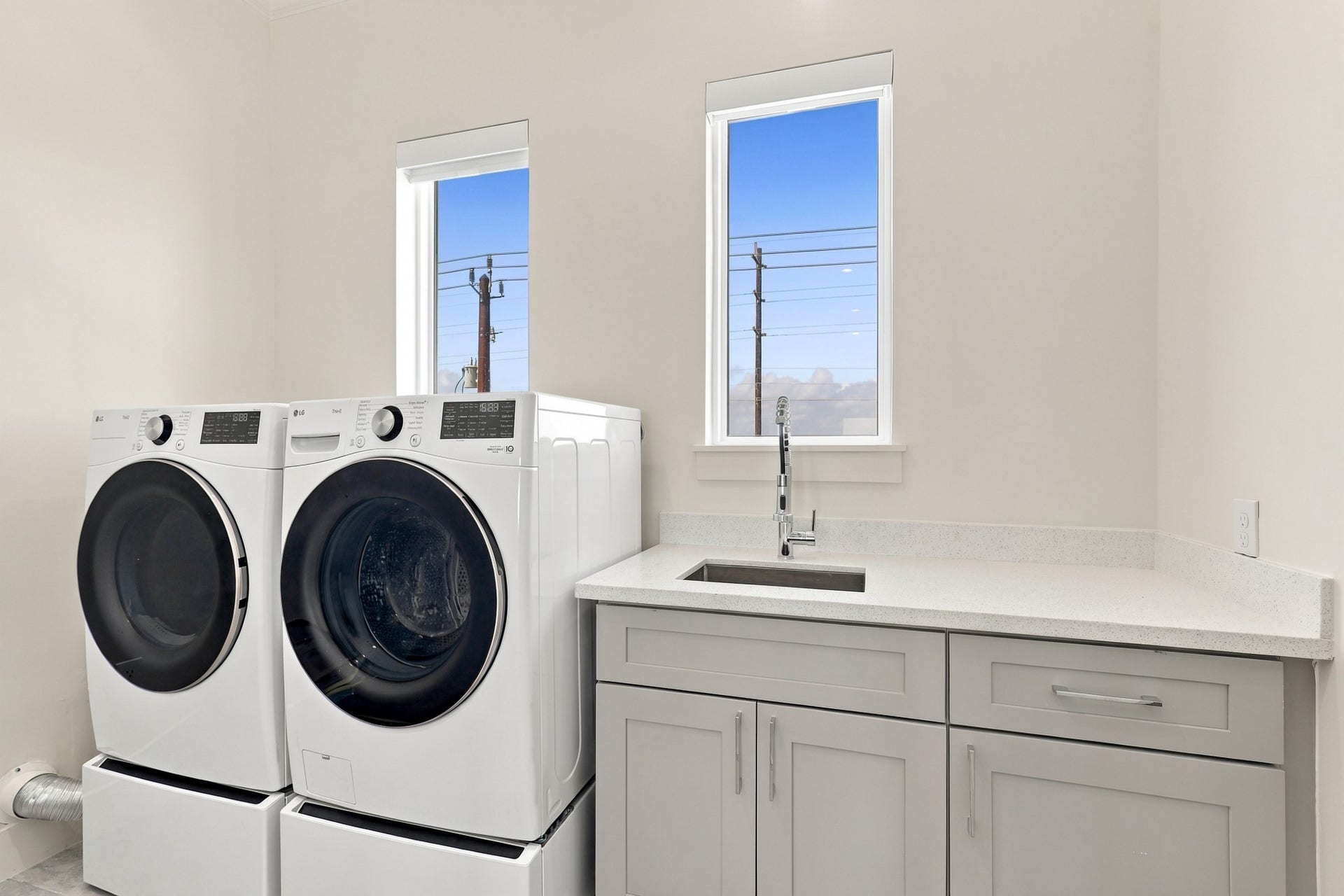 17211 Termini San Luis Pass Rd, Galveston, TX 77554 Bright laundry room with space for side-by-side appliances, a utility sink, and a broad folding counter. Lower cabinetry adds convenient storage for household essentials.
