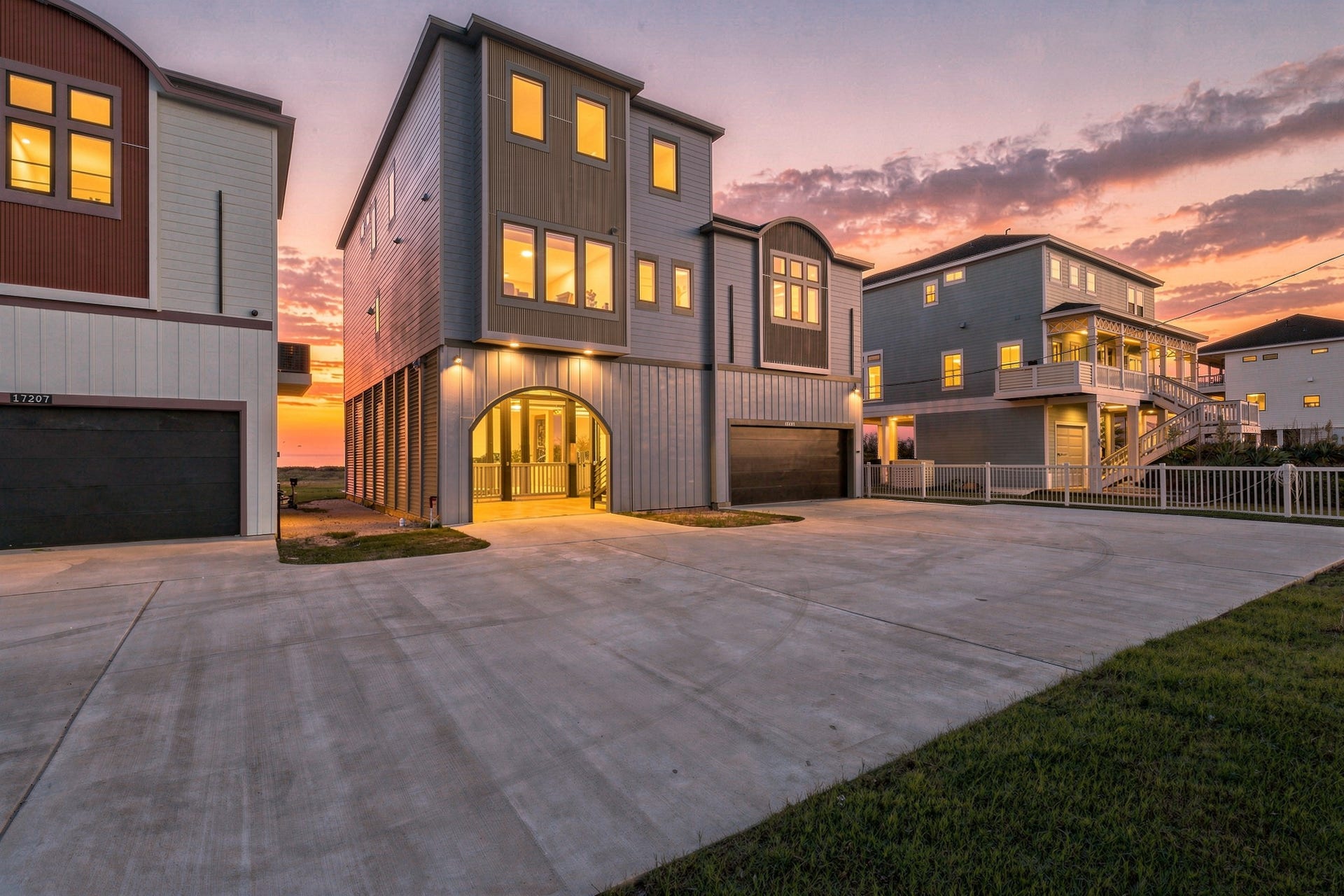 17211 Termini San Luis Pass Rd, Galveston, TX 77554 Contemporary beachfront retreat with striking architectural lines, an illuminated covered entry, and a spacious driveway. Warm evening lighting creates an inviting arrival.