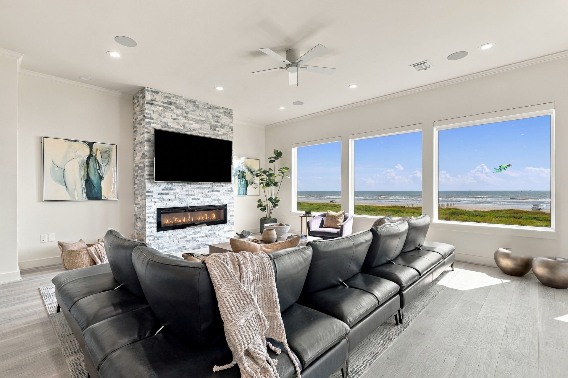 17211 Termini San Luis Pass Rd, Galveston, TX 77554 Broad picture windows frame the beach and Gulf, creating a stunning backdrop for everyday living. A stacked-stone fireplace surround adds texture and warmth to the contemporary interior.
