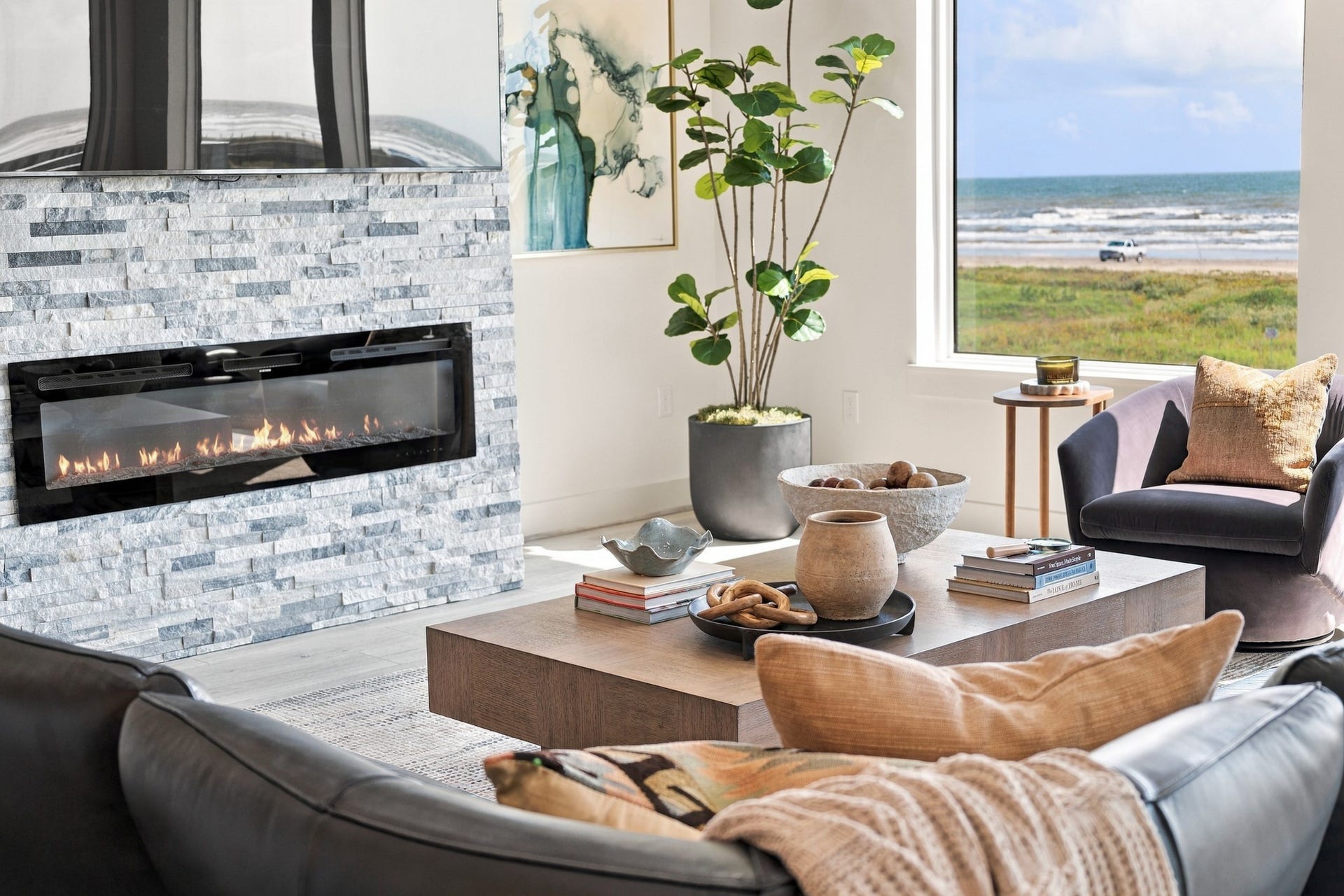 17211 Termini San Luis Pass Rd, Galveston, TX 77554 Fireplace detail
A sleek linear fireplace set within a textured stacked-stone surround creates a striking living-room focal point. The adjacent window frames the shoreline, pairing coastal scenery with an inviting interior.