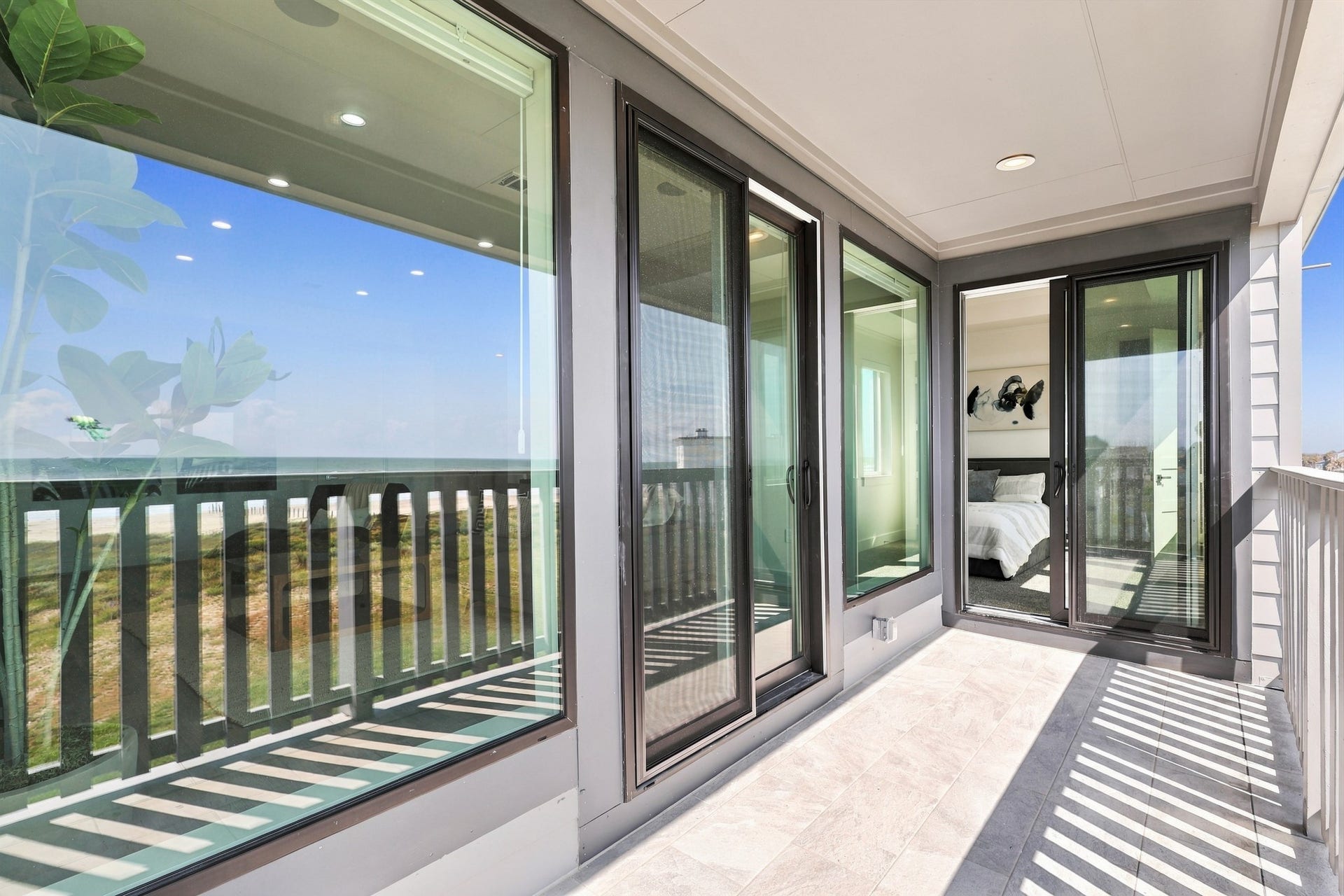 17211 Termini San Luis Pass Rd, Galveston, TX 77554 Bedroom balcony access
Sliding glass doors connect the bedroom to a covered Gulf-facing balcony. Large windows reflect the coastal scenery and carry natural light into the adjoining interior.