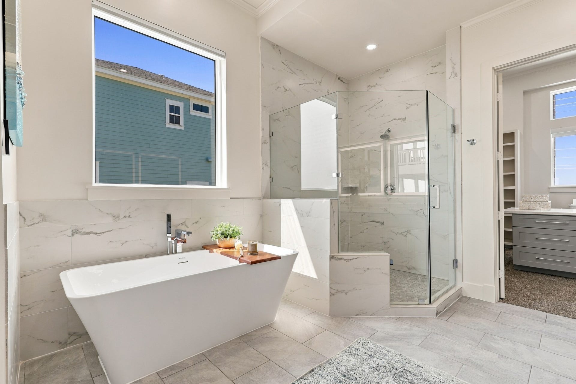 17211 Termini San Luis Pass Rd, Galveston, TX 77554 Soaking tub and shower
A sculptural freestanding tub sits beneath a large window beside the glass-enclosed shower. Coordinating marble-look tile brings a refined, cohesive finish to this relaxing retreat