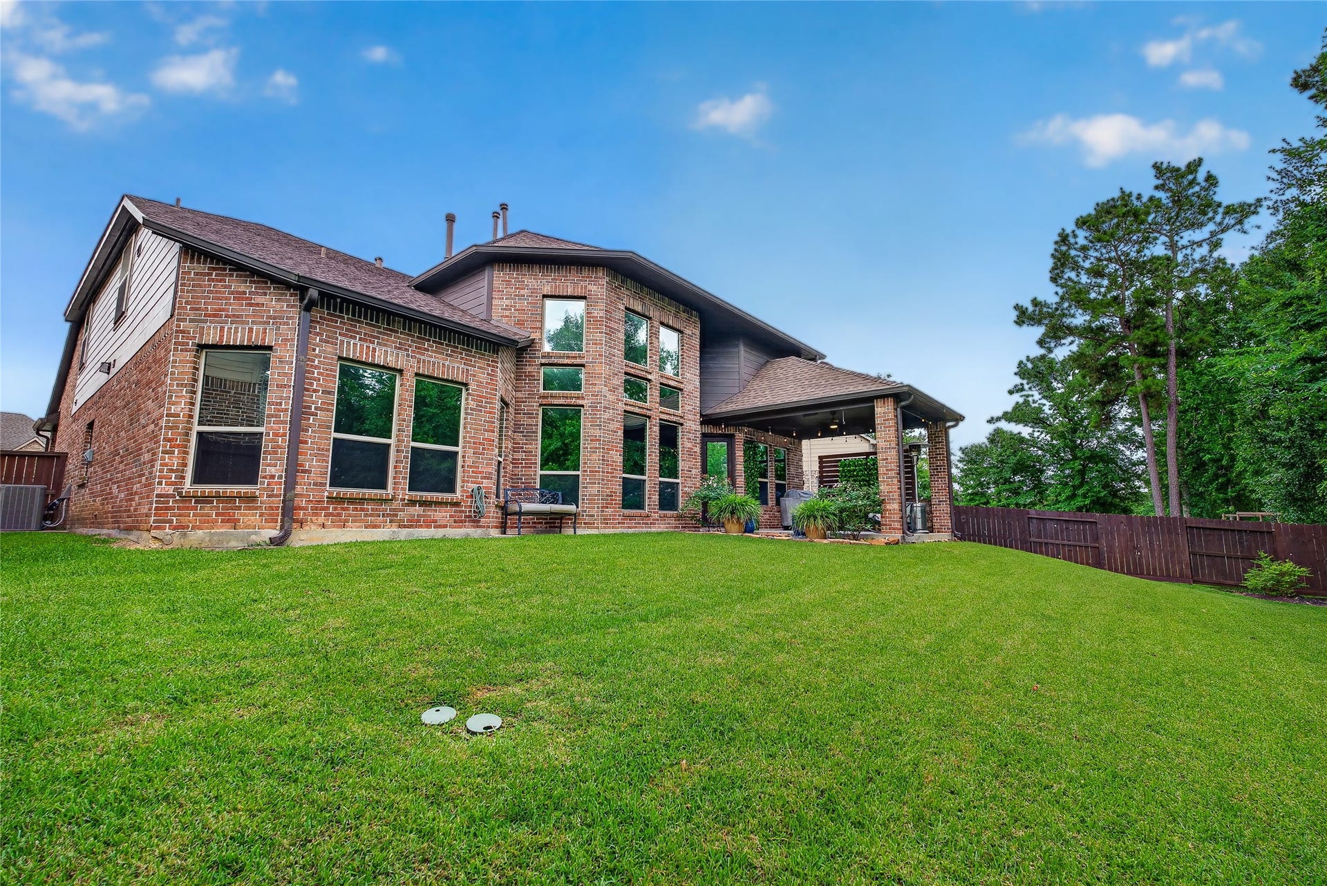 7907 Augusta Creek Court, Spring, TX 77389 This striking brick home features large windows and a covered patio, situated on a spacious, well-maintained lawn with surrounding trees for added privacy.
