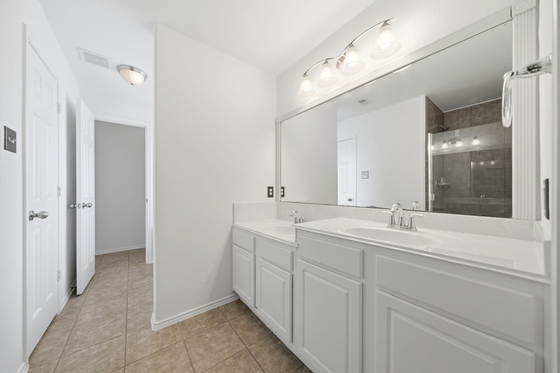 15435 Kaston Drive, Cypress, TX 77433 A extended white vanity with dual sinks and chrome fixtures highlights this primary bath, offering generous cabinet storage and a wide mirror. A separate glass-enclosed shower with tile surrounds and a nearby water closet ensure privacy and routine efficiency.