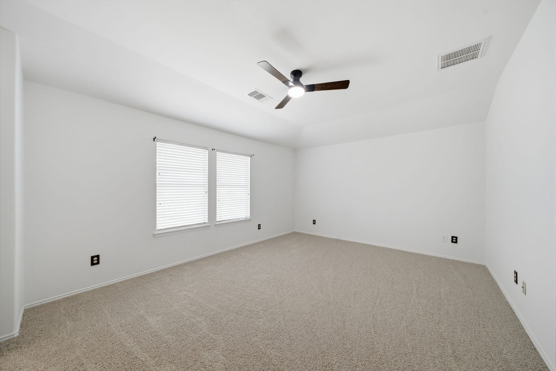 15435 Kaston Drive, Cypress, TX 77433 Neutral carpet flooring, a tray ceiling, and a modern ceiling fan anchor this bright secondary bedroom. Dual windows fill the space with natural light, offering a versatile layout for guest accommodations or a home office.