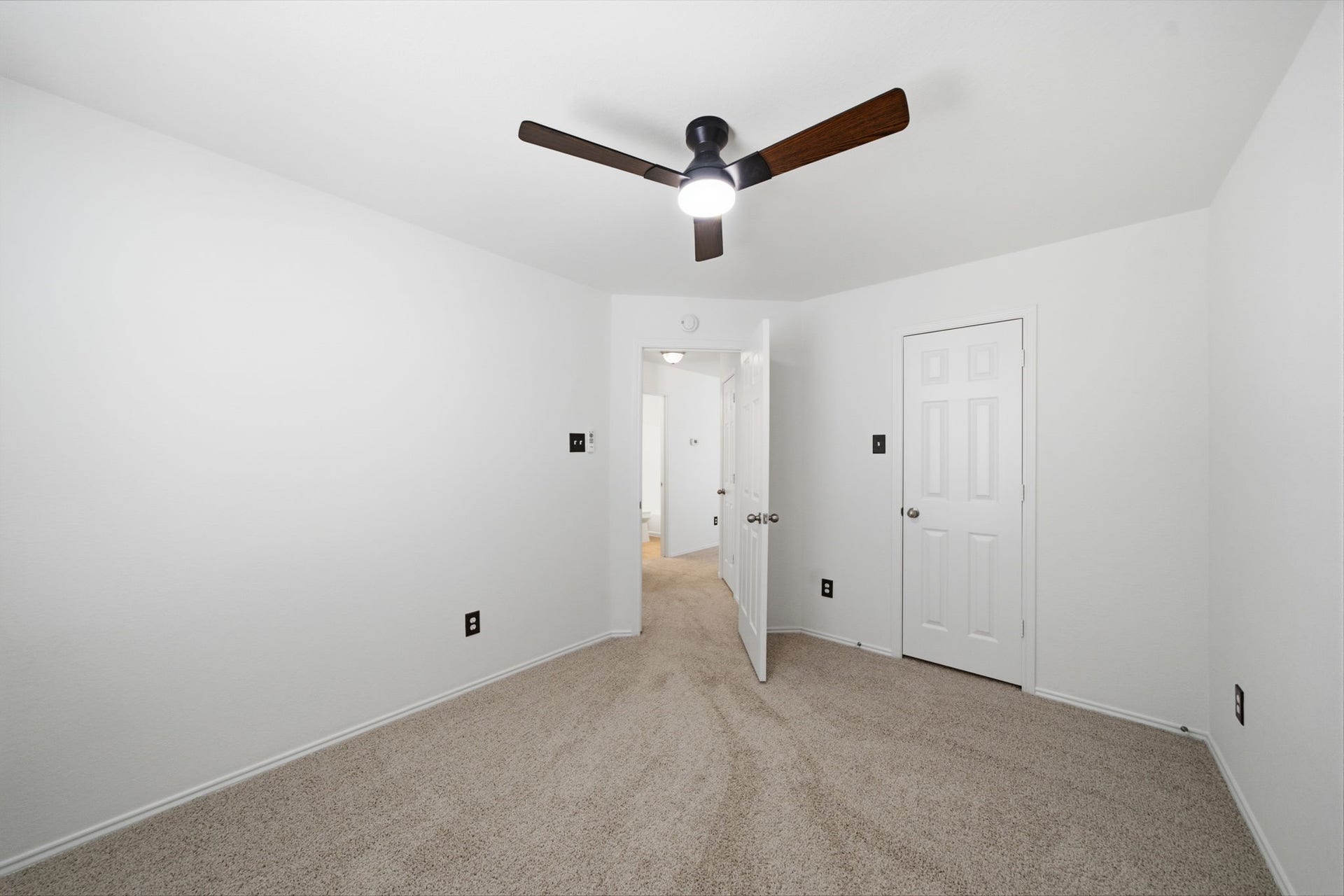 15435 Kaston Drive, Cypress, TX 77433 Soft neutral carpet and a modern dark-blade ceiling fan define this secondary bedroom featuring fresh white paint. A full-size closet door sits beside the entry door, framing an efficient layout for guests or a home office.