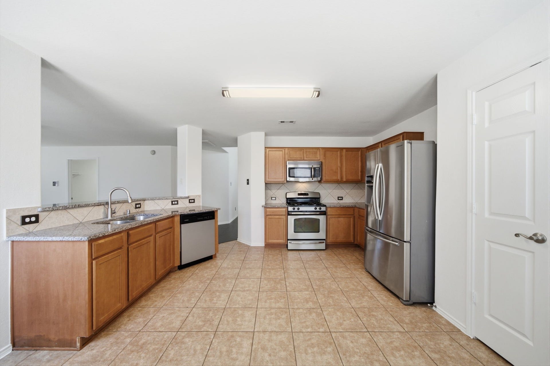 15435 Kaston Drive, Cypress, TX 77433 Spacious and functional, this updated kitchen features warm wood cabinetry, granite countertops, and stainless steel appliances. Tile flooring runs throughout, while a raised breakfast bar offers continuous sightlines into the main living areas.
