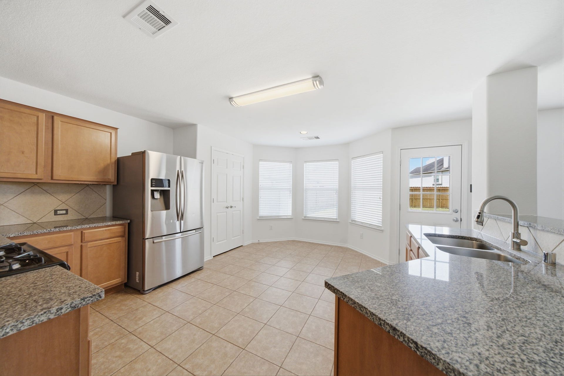 15435 Kaston Drive, Cypress, TX 77433 Warm wood cabinetry and granite countertops frame this updated kitchen, complete with a gas cooktop and stainless steel appliances. A raised breakfast bar overlooks the main living space, while tile flooring leads directly into the sunlit breakfast nook.