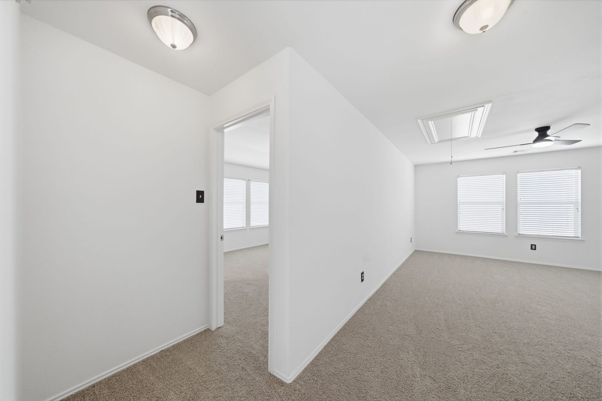 15435 Kaston Drive, Cypress, TX 77433 Neutral carpet flooring and crisp white walls anchor this second-floor hallway connecting the upstairs bedrooms and gameroom. A ceiling fan and flush-mount fixtures illuminate the open layout, while a ceiling hatch provides convenient access to attic storage.