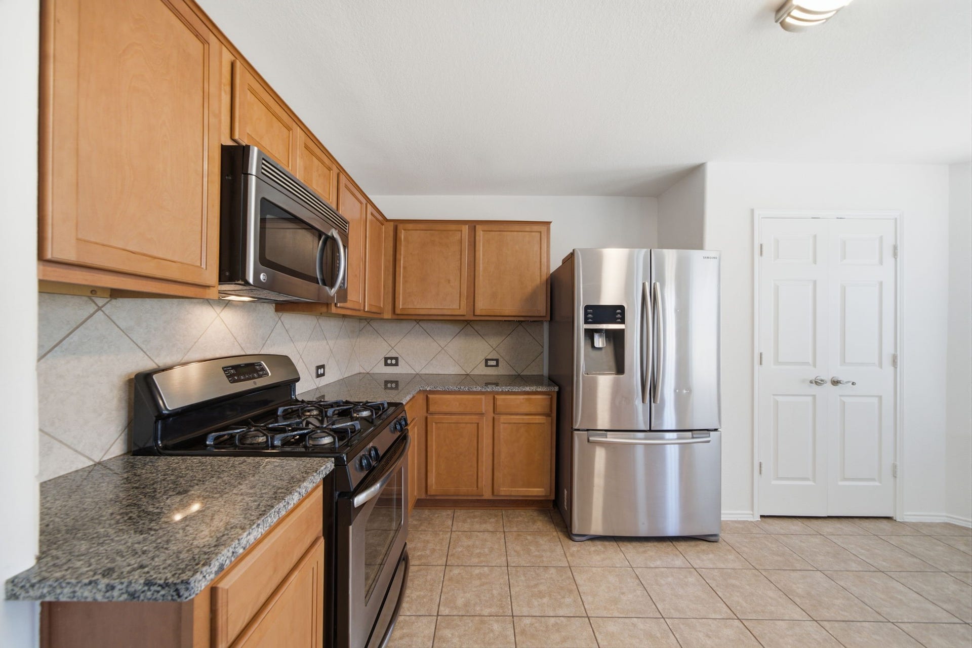 15435 Kaston Drive, Cypress, TX 77433 Stainless steel appliances and rich granite countertops highlight this updated kitchen, outfitted with a gas cooktop and an over-the-range microwave. Warm wood cabinets and a tile backsplash offer plentiful storage and functional workspace.