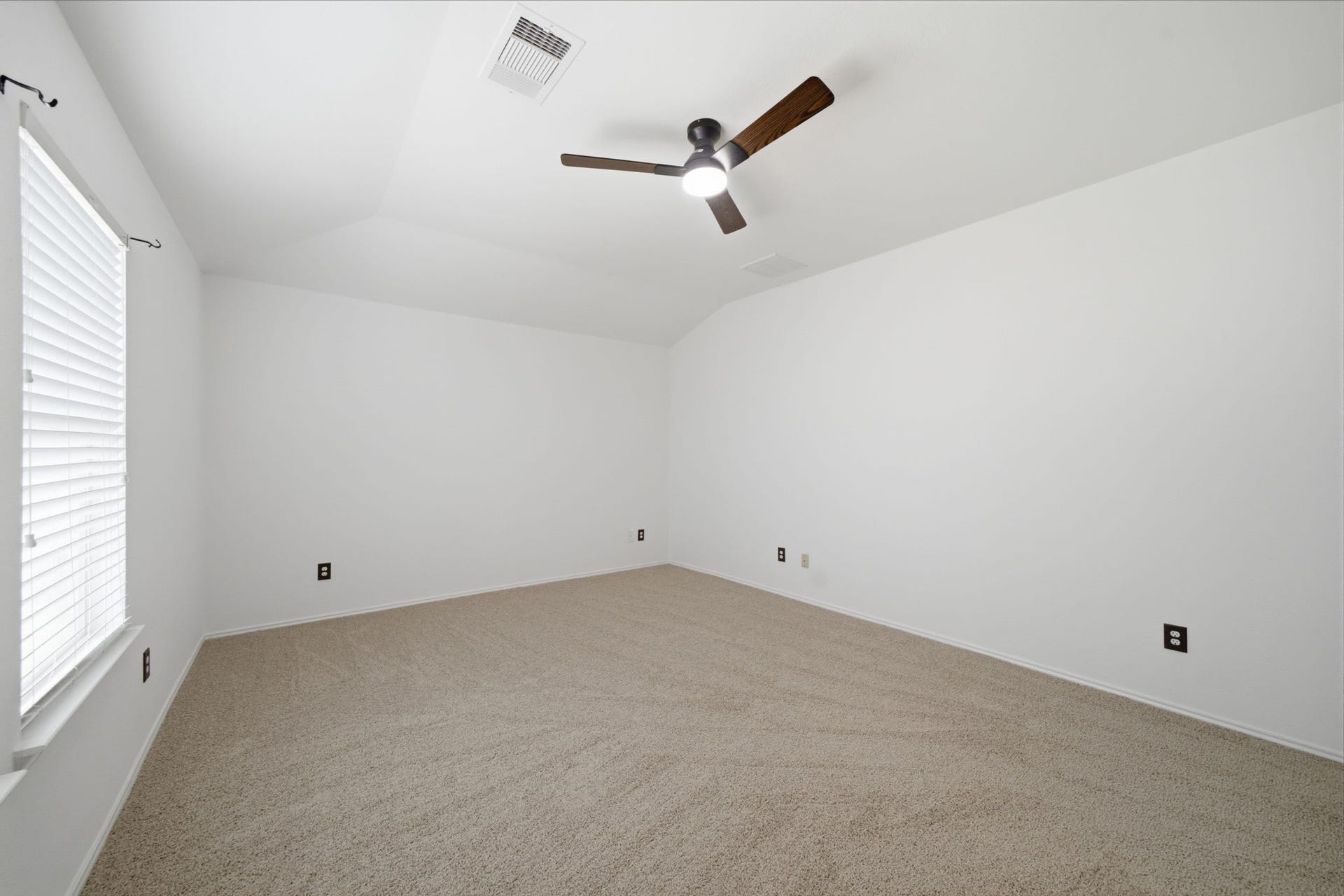 15435 Kaston Drive, Cypress, TX 77433 Vaulted ceilings and soft carpet flooring highlight this versatile secondary bedroom. A dark wood-blade ceiling fan and wide window create a comfortable, airy space ready for any bedroom arrangement.