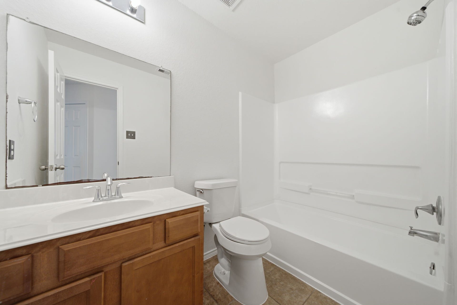 15435 Kaston Drive, Cypress, TX 77433 Tiled flooring and a full tub/shower combination with a durable white surround define this functional secondary bathroom. A rich wood vanity provides storage beneath an extended mirror and bright vanity lighting.