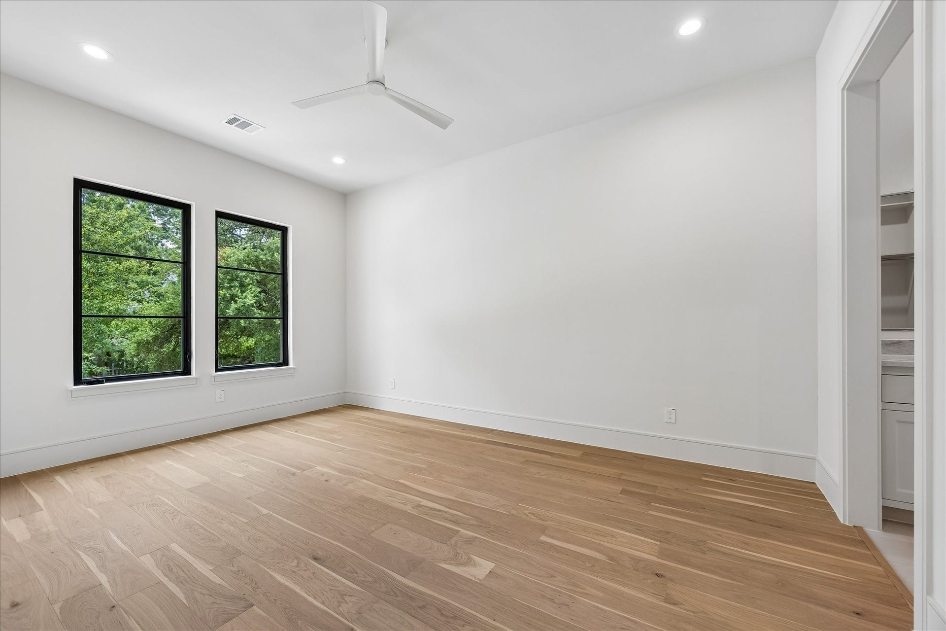 316 W 30th Street, Houston, TX 77018 Black framed windows fill this secondary bedroom with natural light, while wide plank hardwoods and an ensuite bath create a comfortable, private retreat for family or guests.