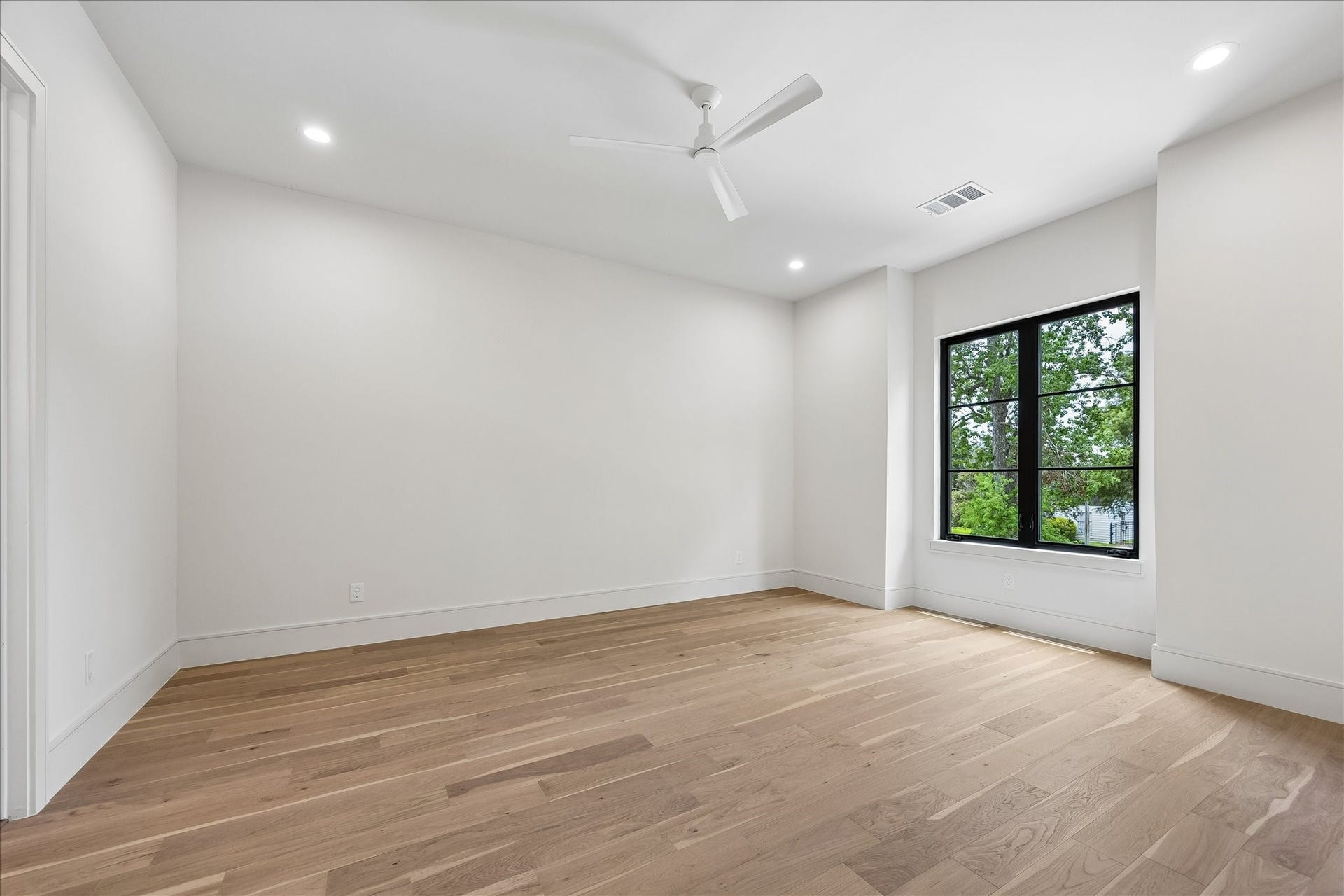 316 W 30th Street, Houston, TX 77018 Wide plank wood floors, and oversized black framed windows create a bright, inviting secondary bedroom. An attached ensuite bath provides comfort and privacy for family members or overnight guests.