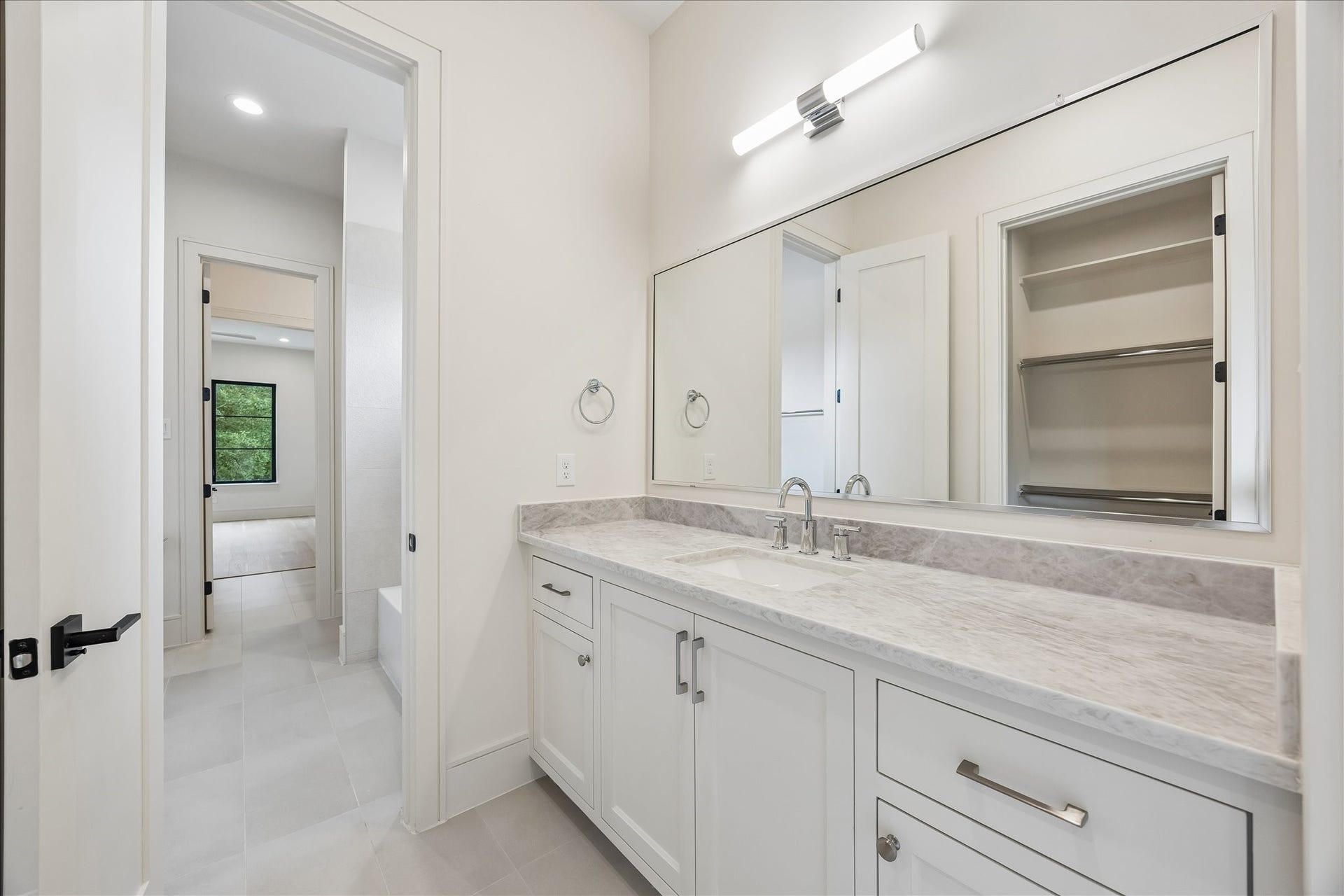 316 W 30th Street, Houston, TX 77018 Shared bath features a quartz topped dual vanity, oversized mirror, and a spacious walk in linen closet for added convenience. Bright finishes and a thoughtfully designed layout make mornings easy for adjoining bedrooms.