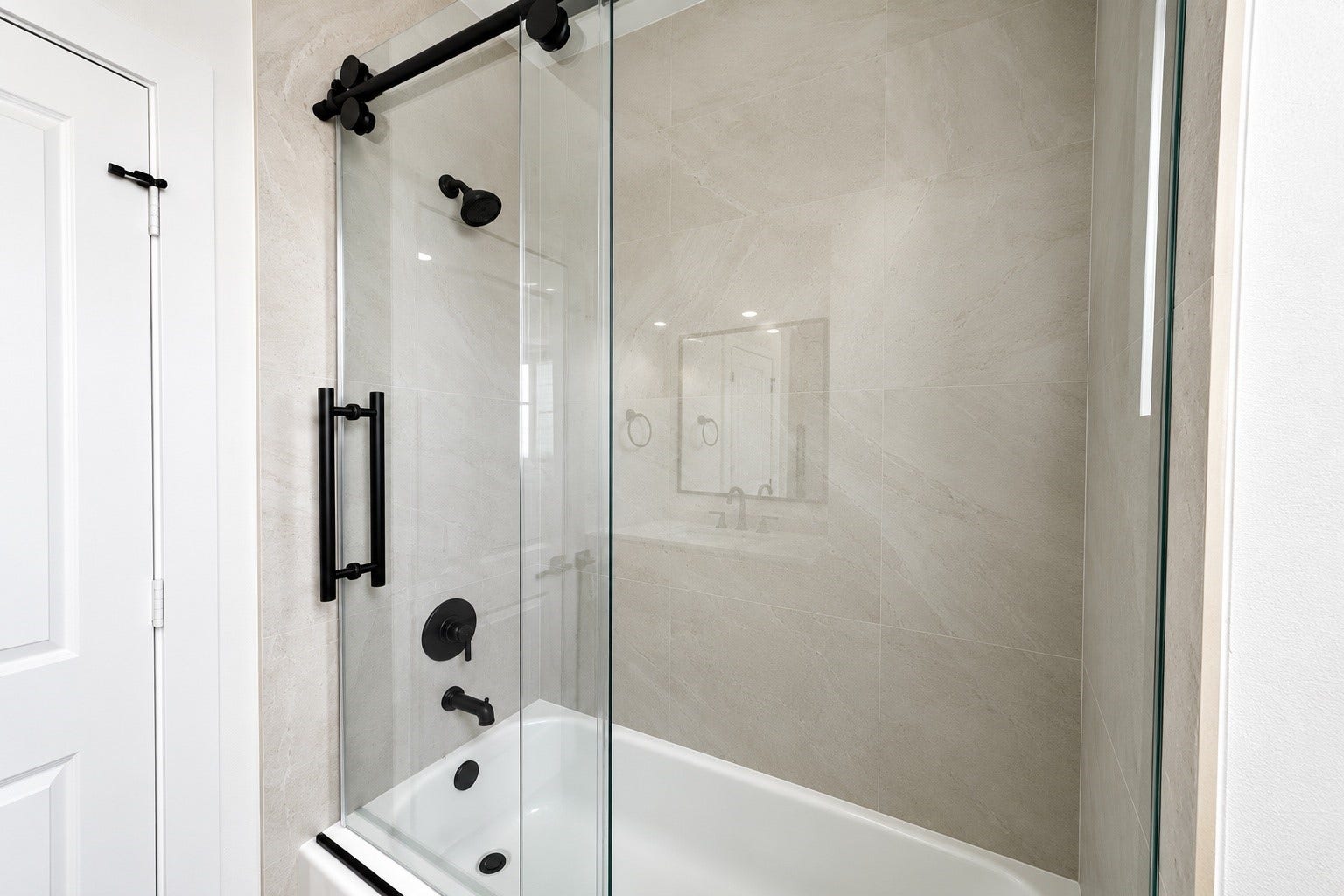 509 Hillwood Heights Drive, Houston, TX 77091 Sleek and modern bathroom featuring a glass-enclosed shower with elegant matte black fixtures and neutral tile walls.