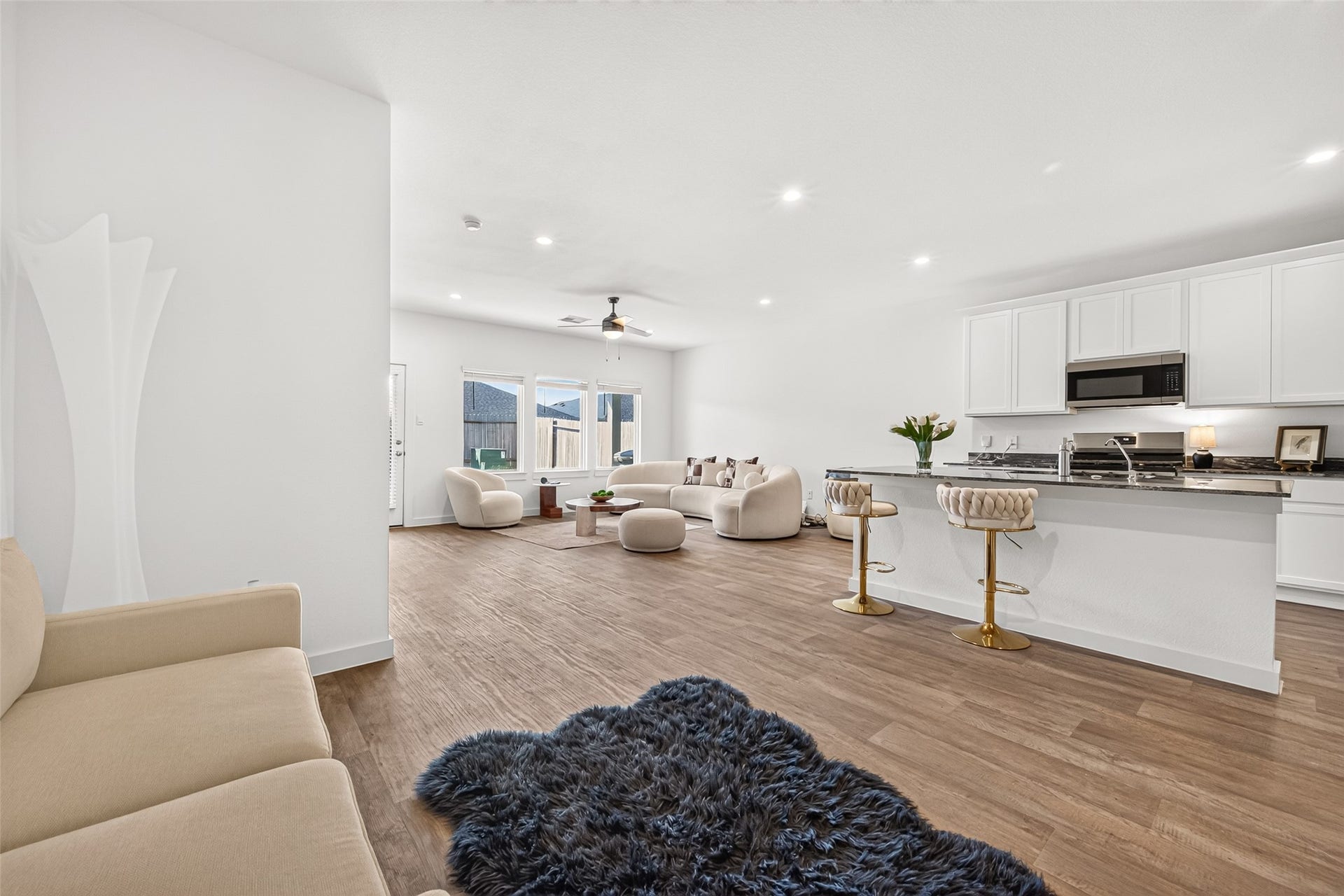 Bright, open-concept living area featuring sleek hardwood floors, a modern kitchen with a spacious island, and ample natural light from large windows.