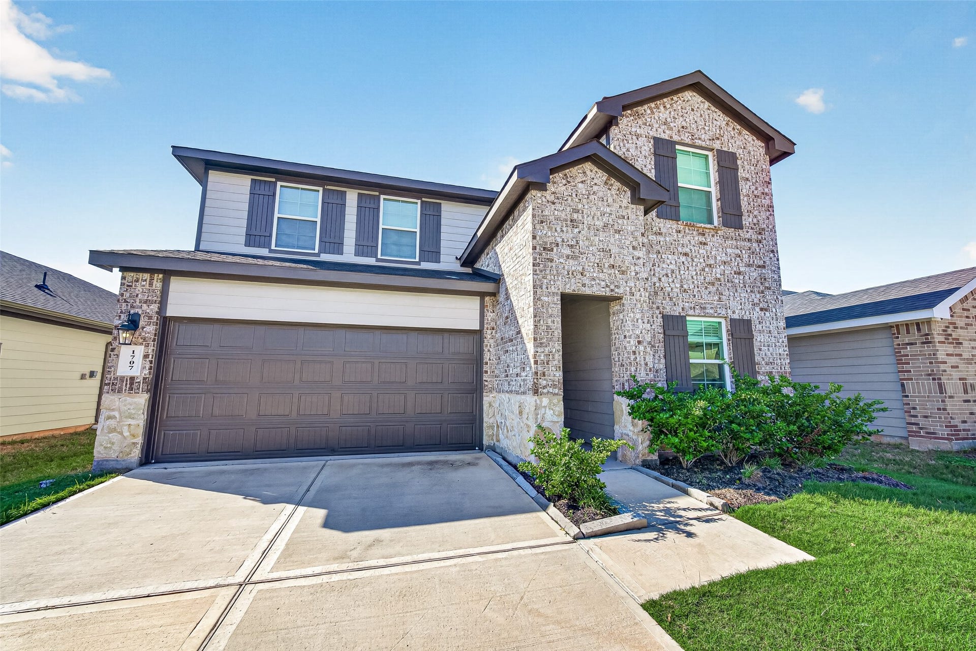 Charming two-story home with a modern brick faade, featuring a spacious two-car garage and well-maintained landscaping.