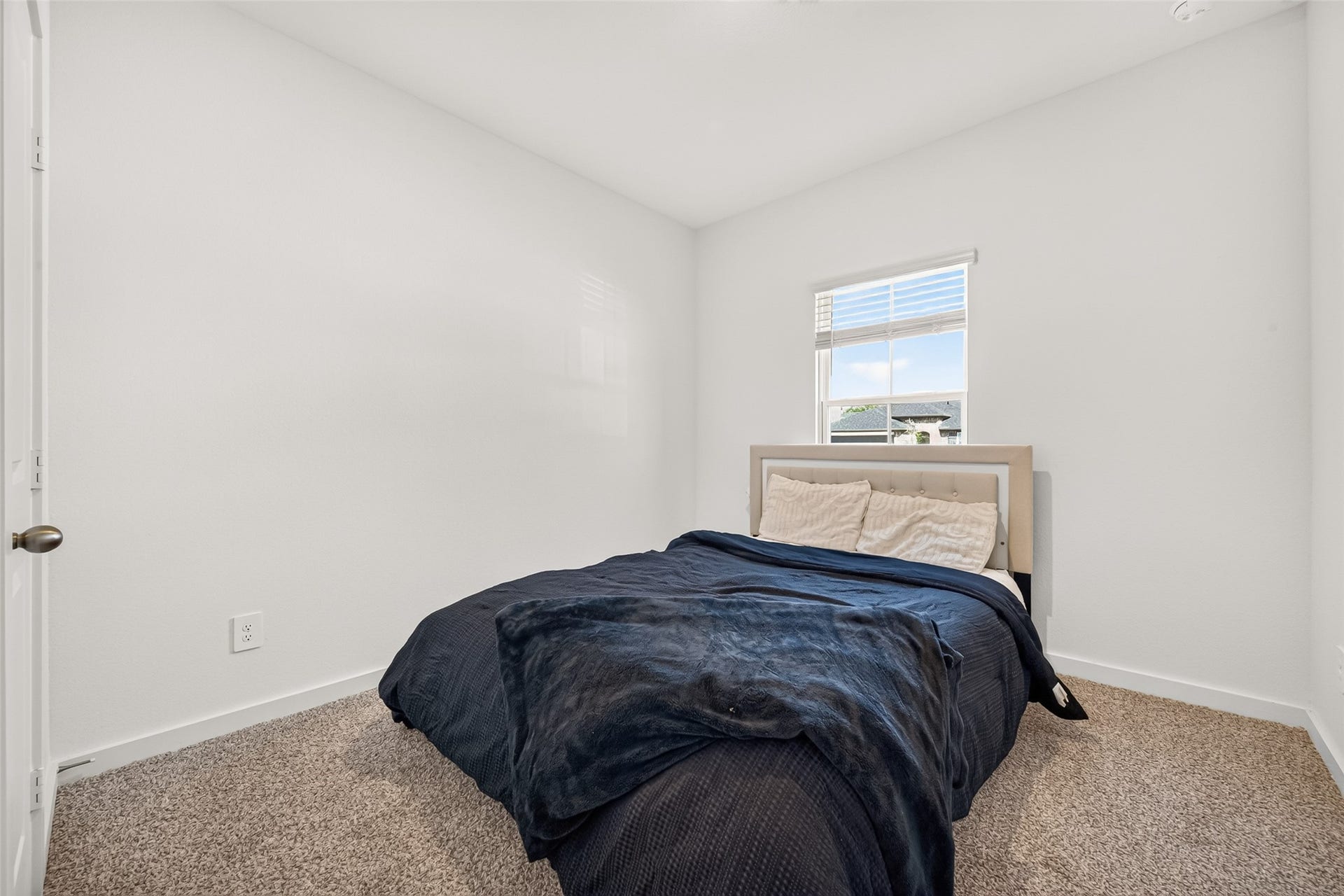 Cozy bedroom with soft carpeting and natural light streaming through a window, offering a peaceful retreat. (1st floor)
