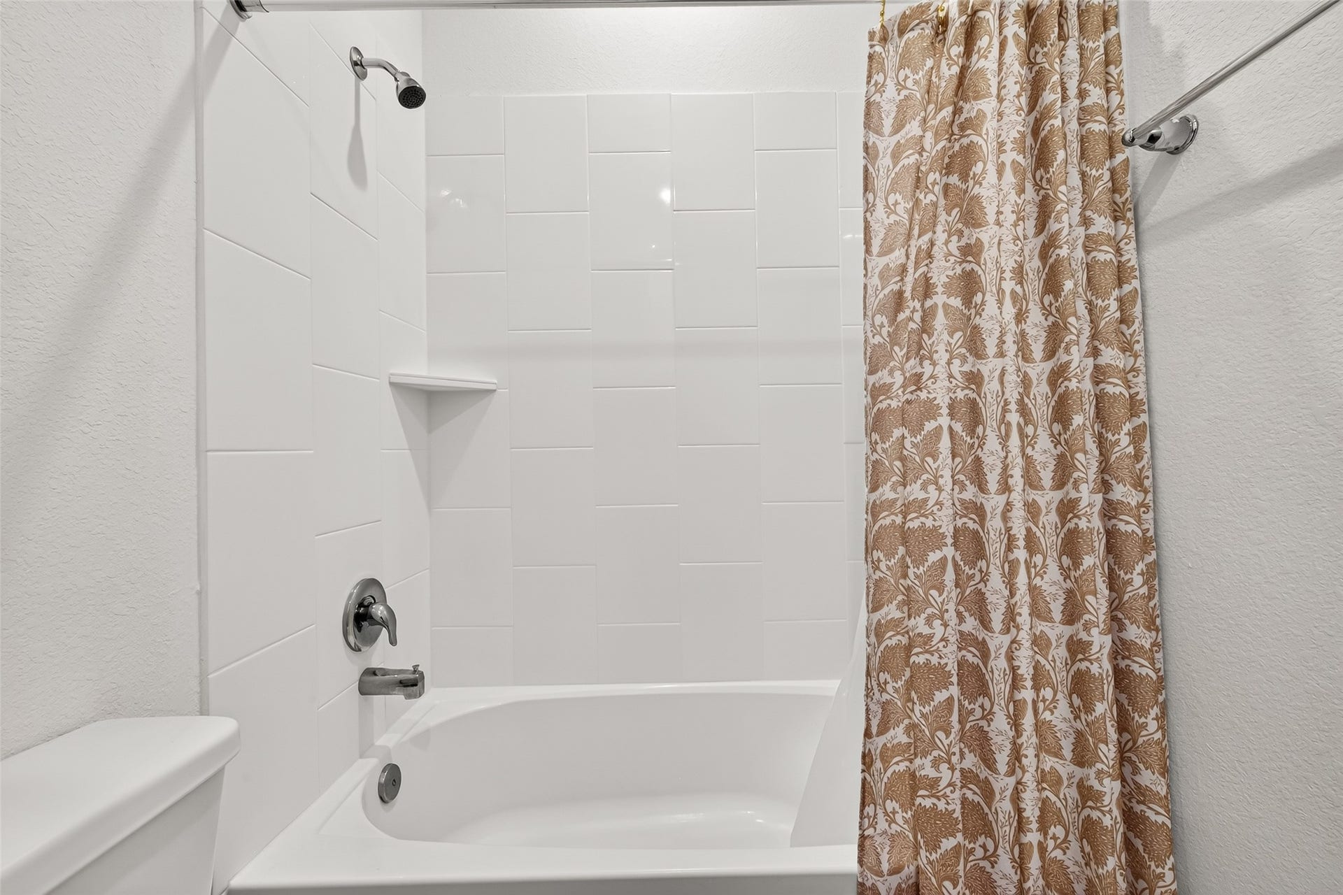 Bright and inviting bathroom featuring a sleek white tub with modern fixtures and a stylish patterned shower curtain for a touch of elegance.