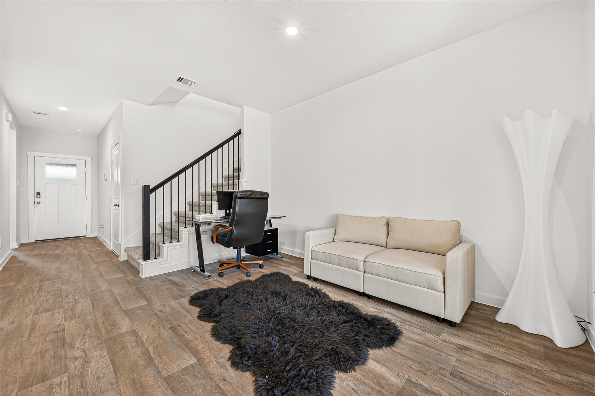 Bright entryway with stylish wood flooring, modern staircase, and a cozy seating area, perfect for welcoming guests.