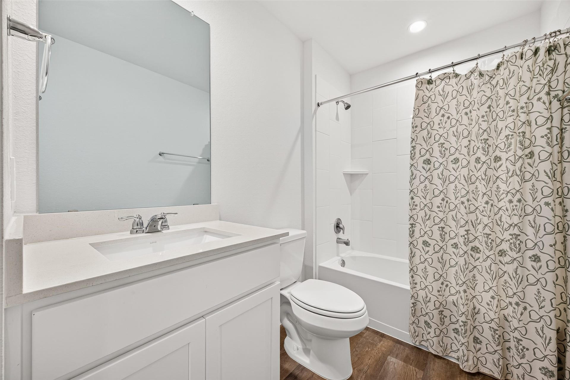 Bright and modern bathroom featuring a sleek vanity, large mirror, and a shower-tub combo with a stylish patterned curtain.