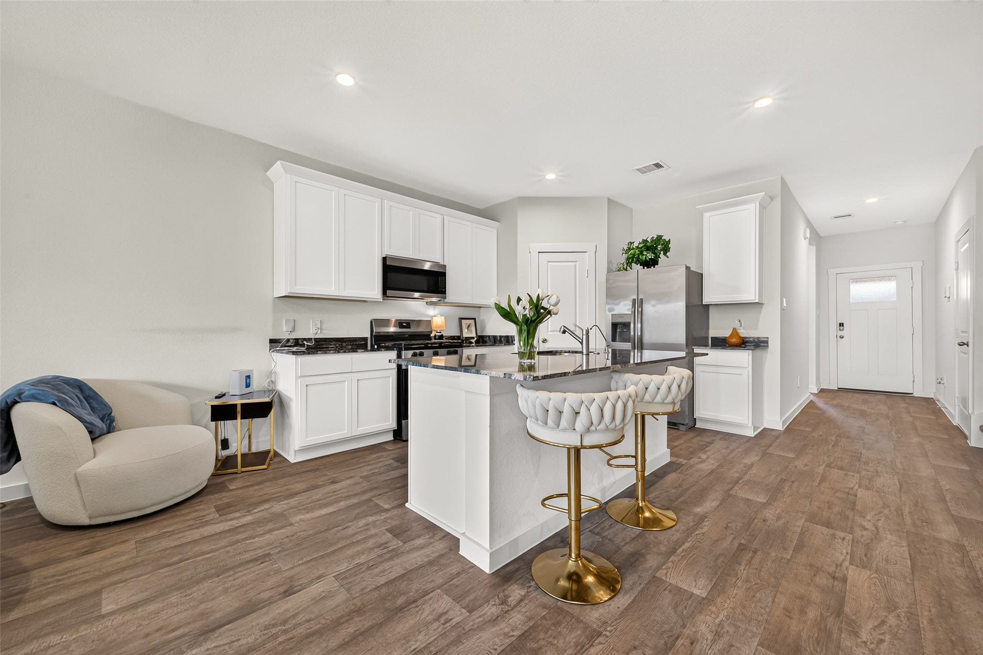Modern kitchen with sleek white cabinetry, stainless steel appliances, and a stylish island featuring elegant barstools.