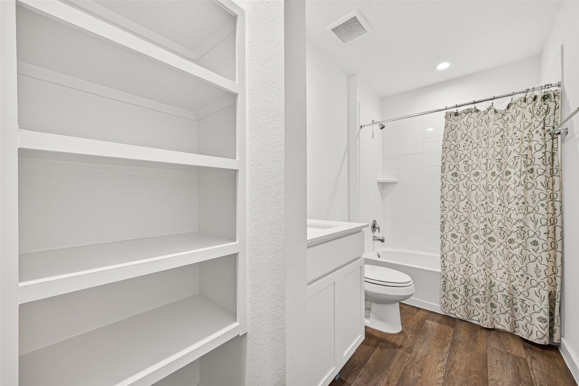 Bright and modern bathroom featuring built-in shelving, a sleek vanity, and a shower-tub combo with a stylish curtain.