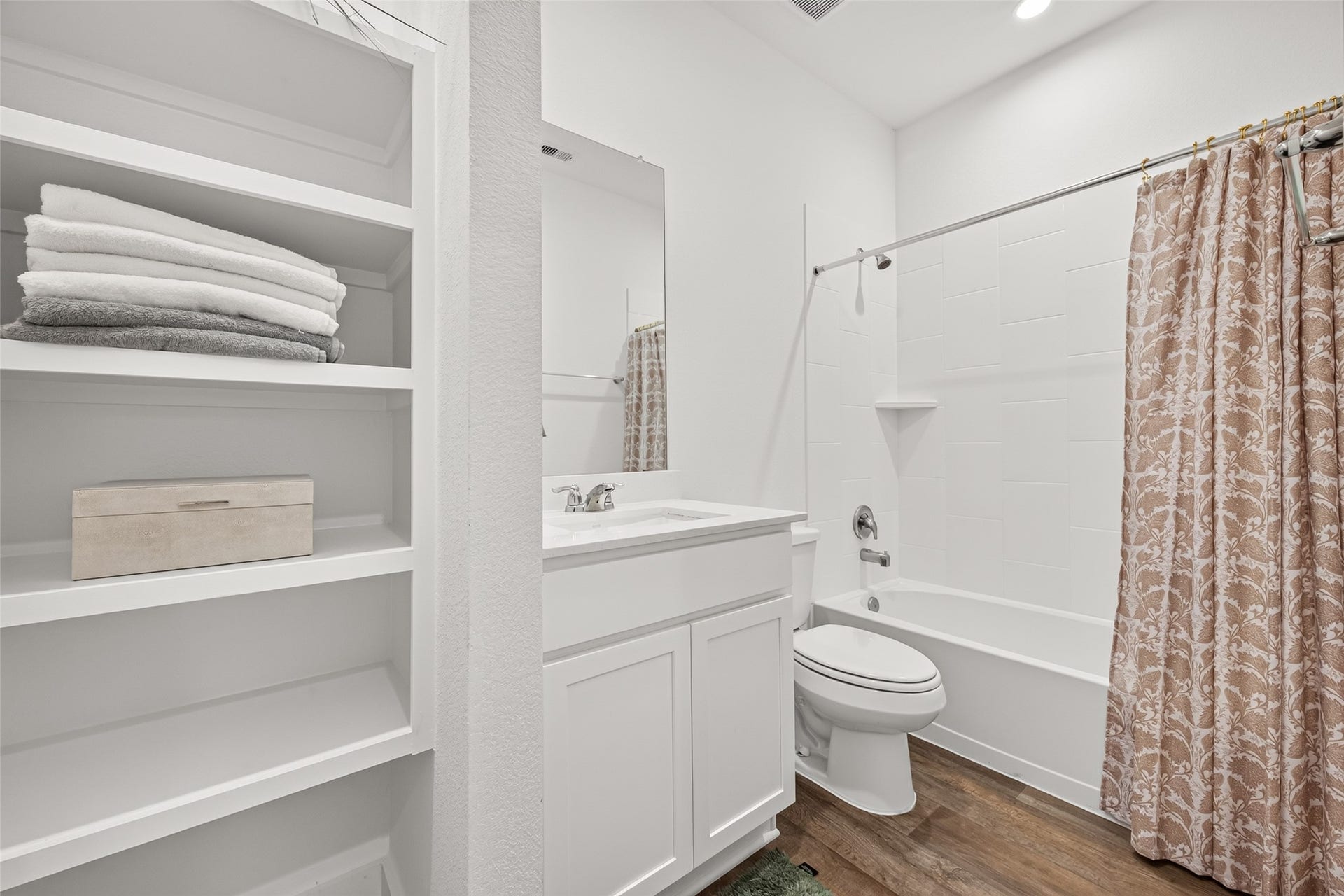 Charming bathroom with a clean, modern design featuring a white vanity, built-in shelving for storage, and a shower-tub combo with stylish tilework.(1st floor)