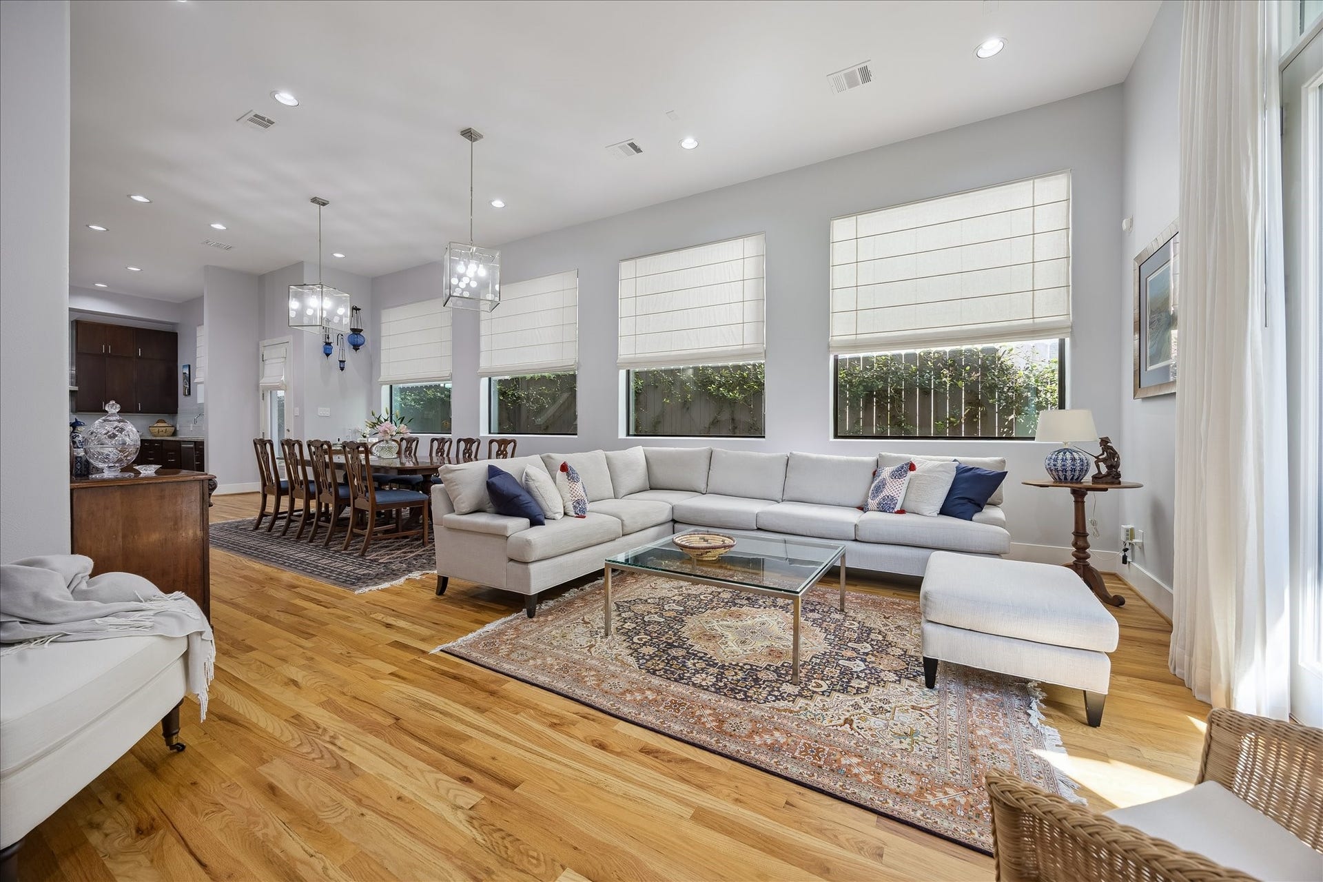 Another view of the living room and dining room with its beautiful wood floors, substantial windows and designer window treatments.