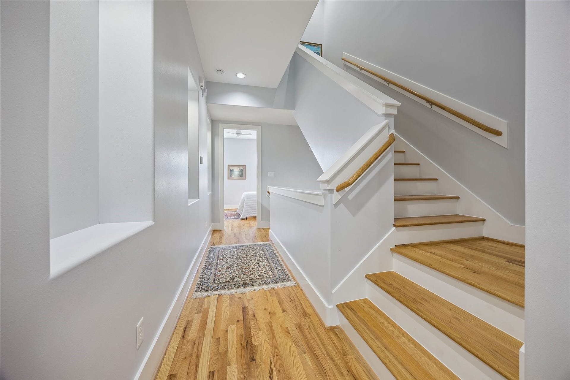 Elegant gallery style hallway between the primary and secondary bedrooms with rich wood floors and recessed art niches.