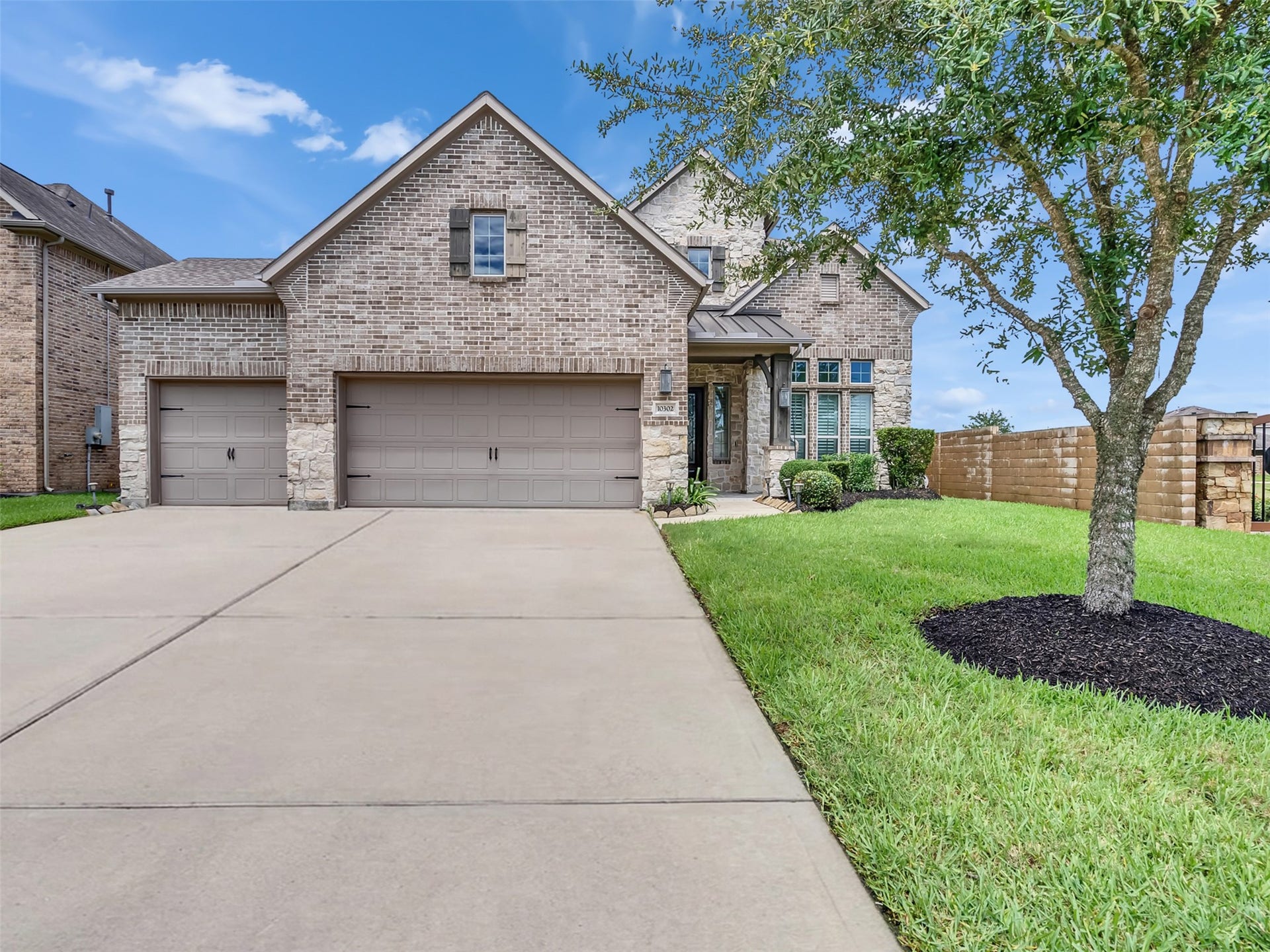 10302 Muir Peak Drive, Rosharon, TX 77583 Charming two-story brick and stone home with a well-maintained front yard, attached 3-car garage, and welcoming entryway.