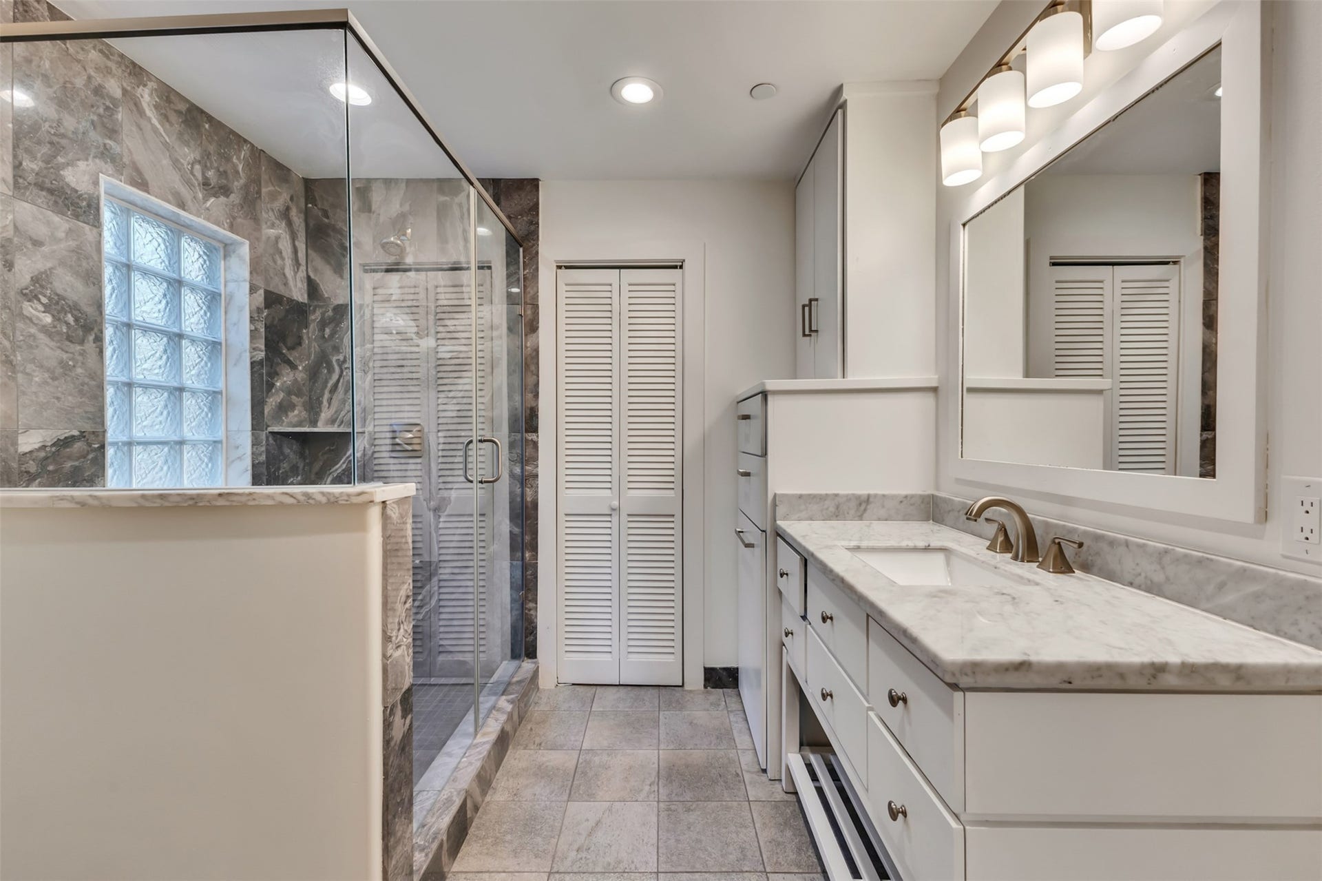 Modern bathroom with a large glass shower and plenty of built in cabinet/drawer space.