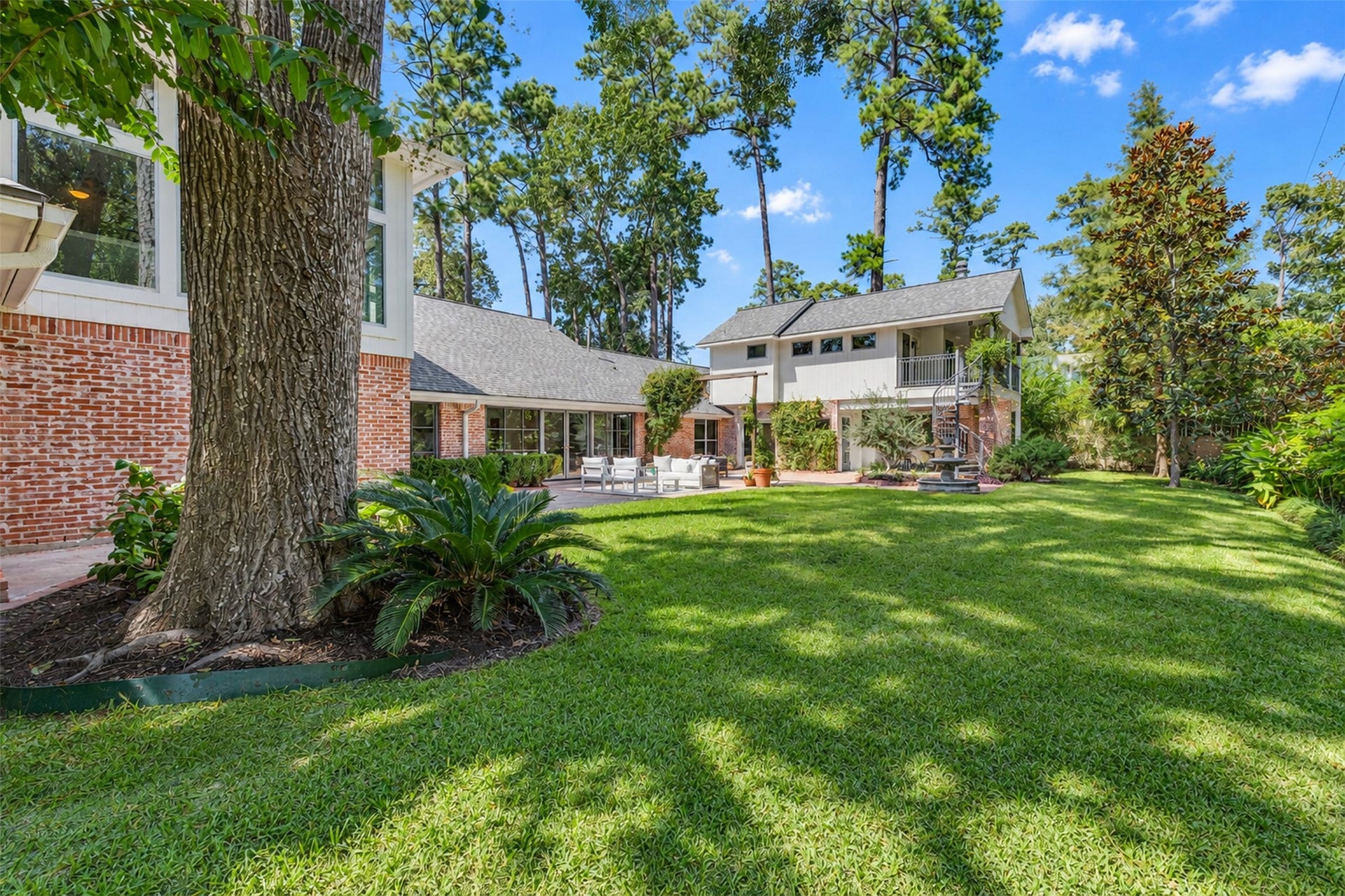 Generous side yard featuring a charming water fountain and expansive green lawn, offering a peaceful, private backdrop for relaxing.