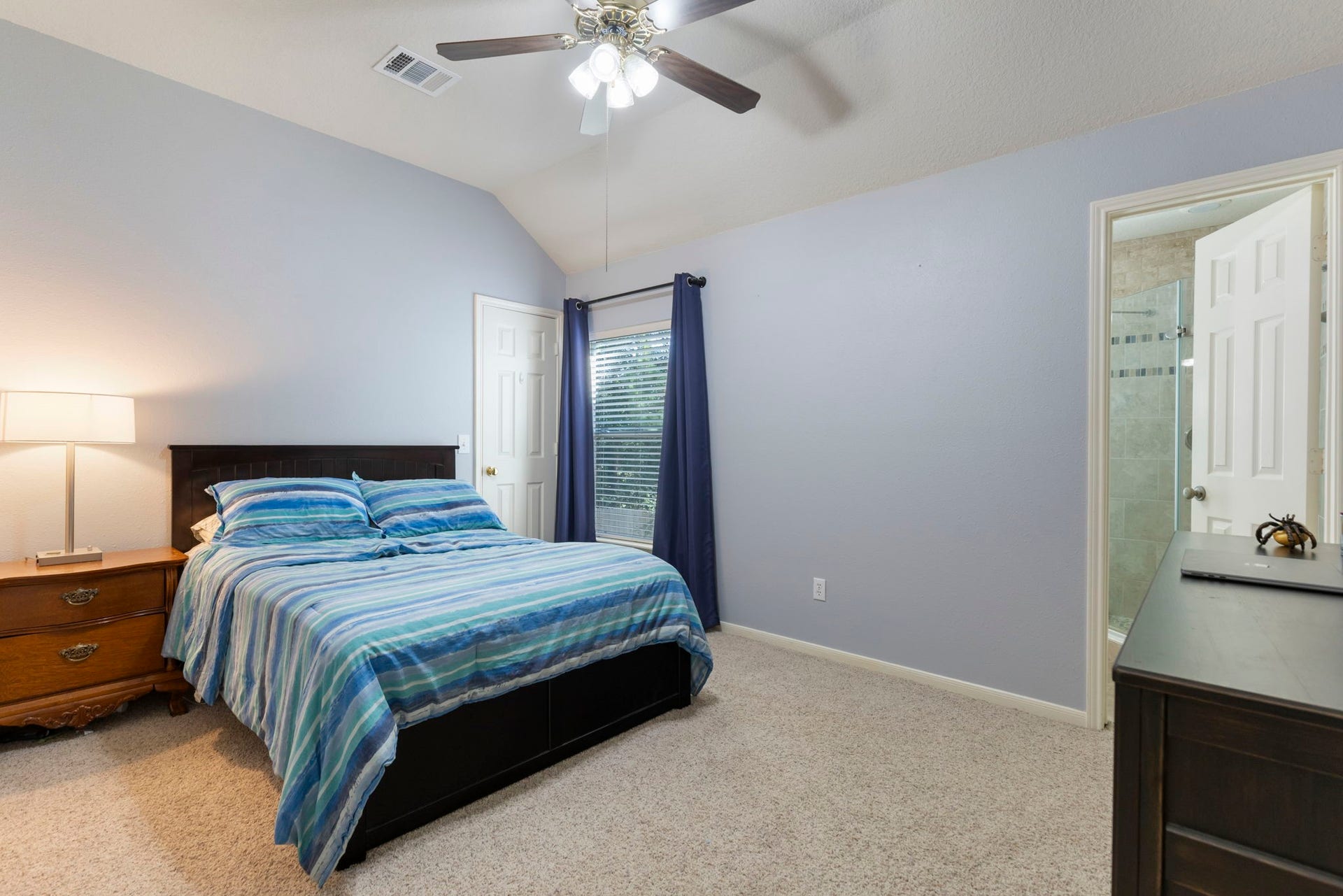 98 W Night Heron Place, The Woodlands, TX 77382 A spacious secondary bedroom with vaulted ceilings, soft natural light, and a private en-suite bath creates the perfect guest or teen retreat.