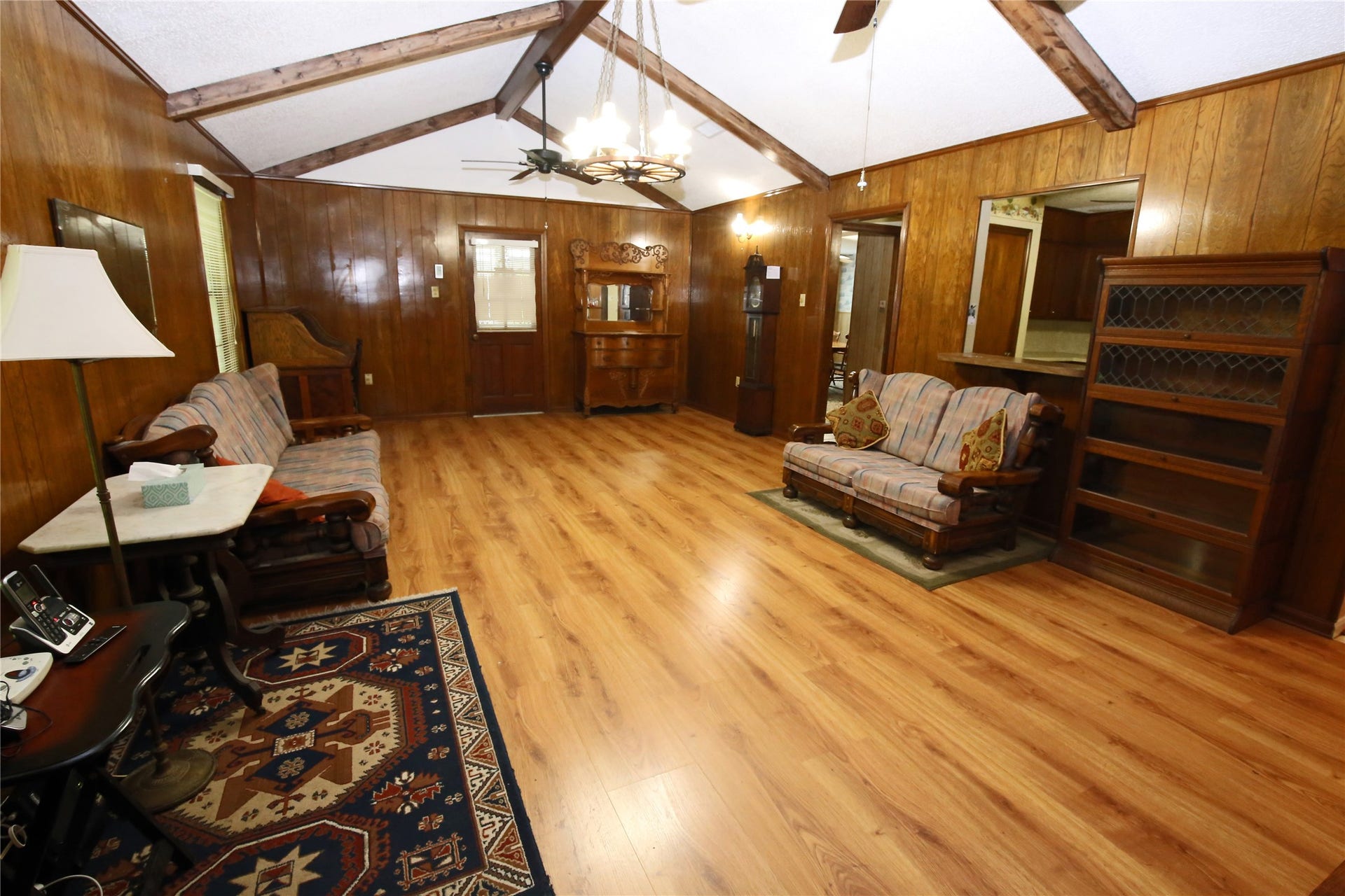 3804 Shady Lane, Santa Fe, TX 77517 Spacious living room featuring warm wood paneling, vaulted ceilings with exposed beams, and elegant hardwood floors. Perfect for cozy gatherings and relaxation.