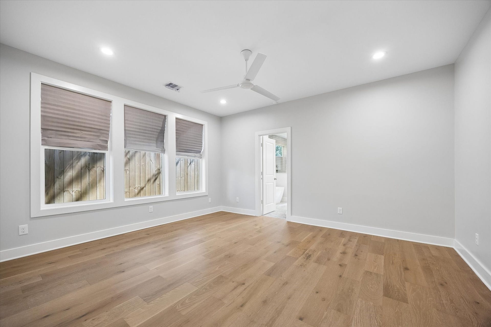 10659 Mayfield Road, Houston, TX 77043 This spacious primary bedroom features large windows, creating a bright and welcoming space. The hardwood floors add a touch of elegance, while the ceiling fan ensures comfort. The room also includes direct access to a luxurious en-suite bathroom.