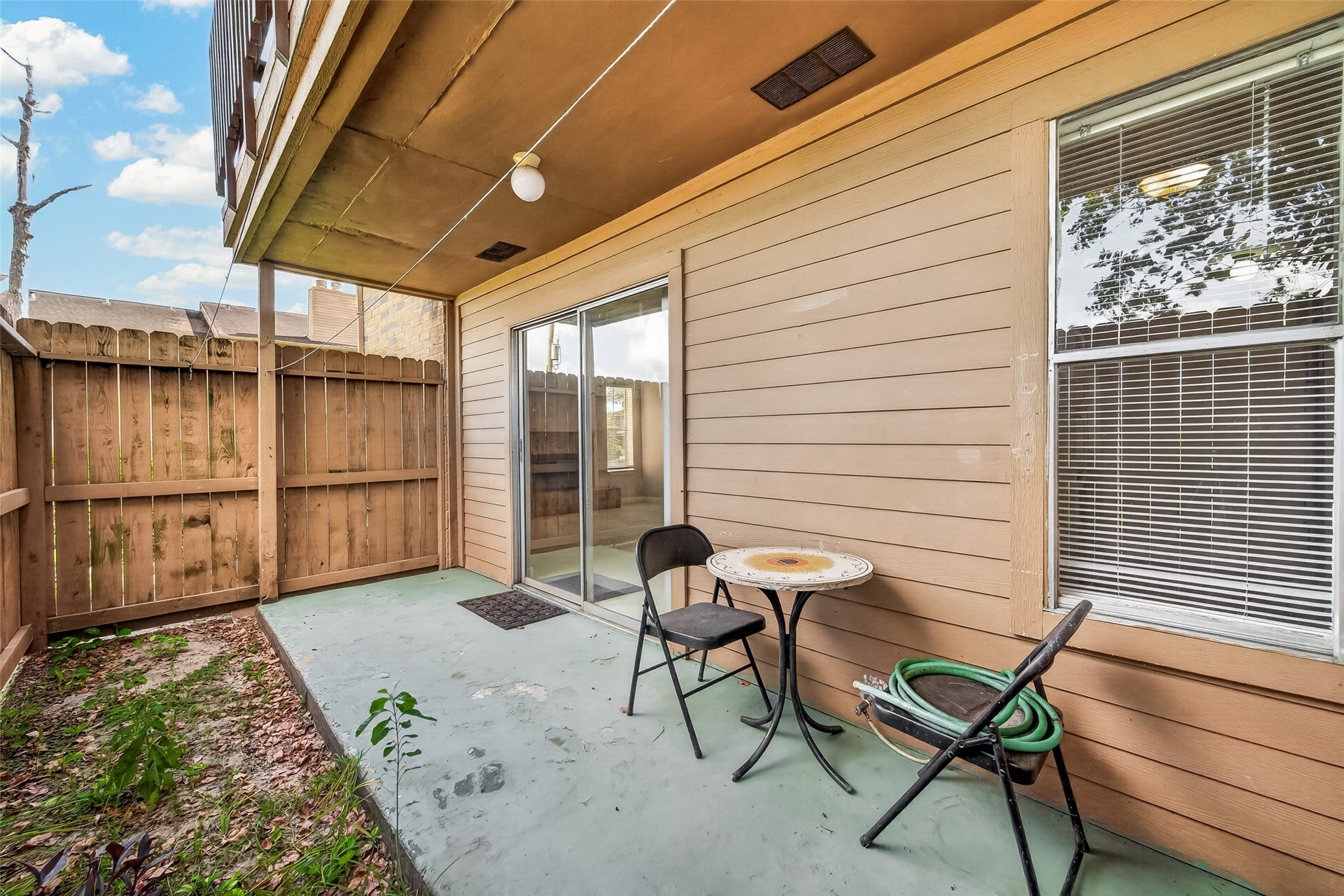 10555 Turtlewood Court, #1006, Houston, TX 77072 Charming patio space with privacy fencing, offering a cozy spot for relaxation or outdoor dining, complete with sliding doors for easy indoor-outdoor access.